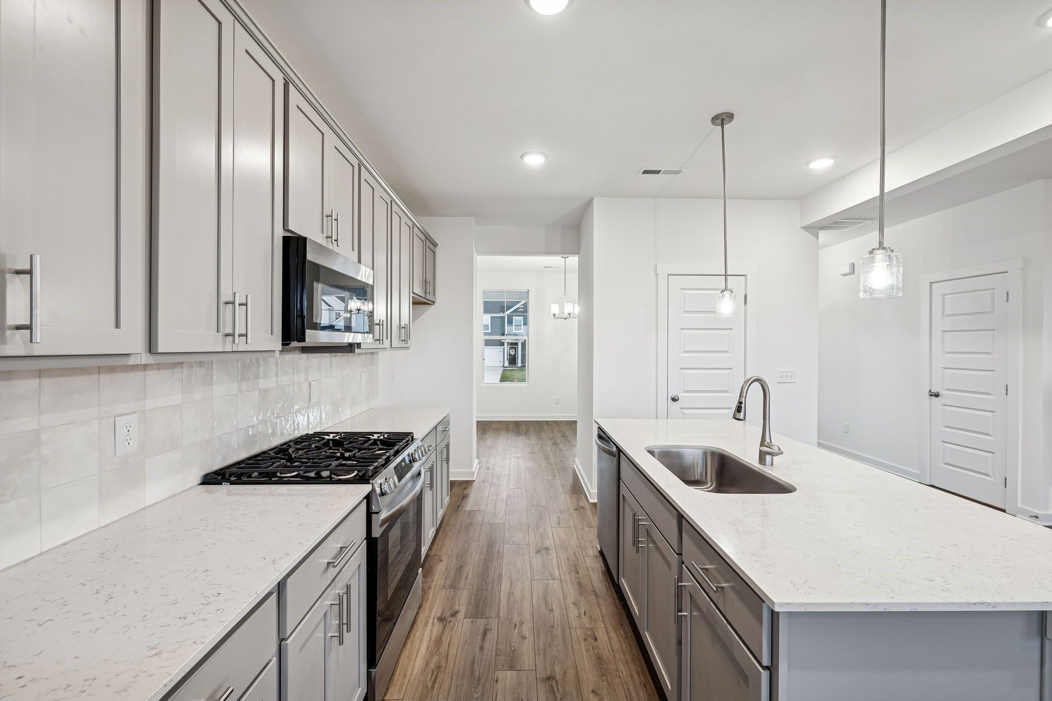 Modern kitchen with quartz countertops, shaker cabinets, stainless appliances, and island in The Willow floor plan, Calista Farms, White House, TN