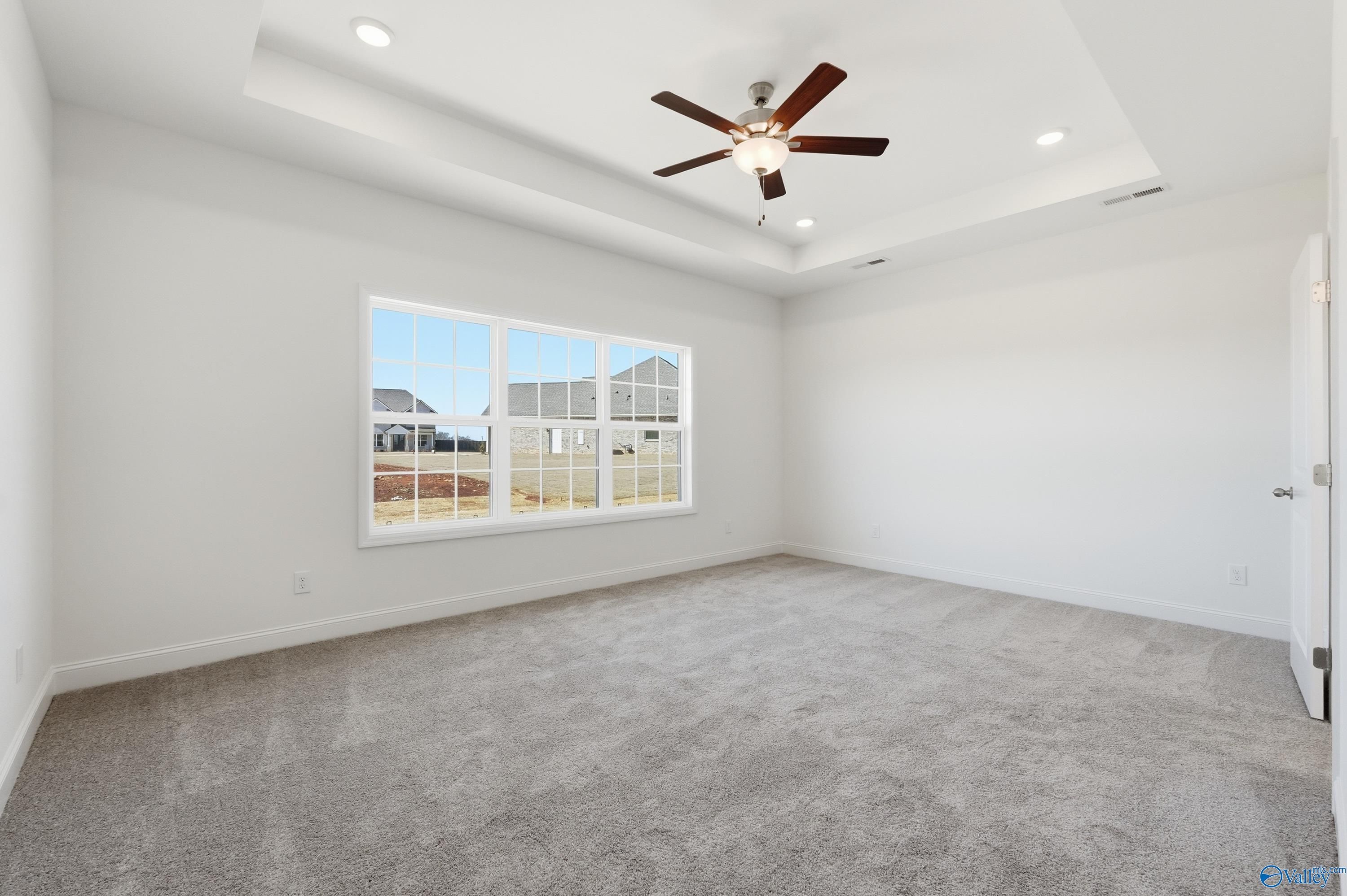 Bright bedroom with large window, ceiling fan, recessed lights, and gray carpet in The Montgomery floor plan, Meridianville, Alabama