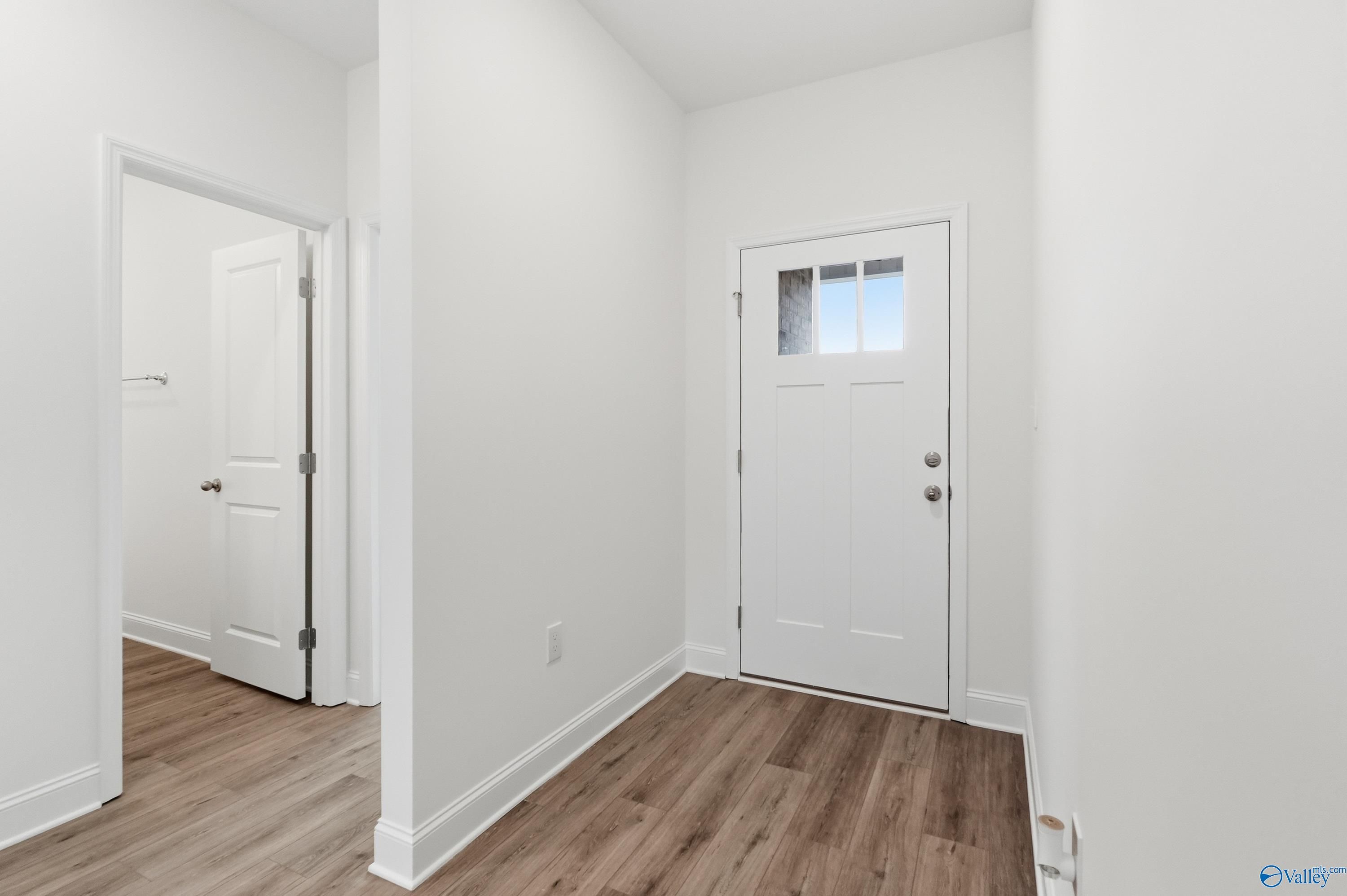 Bright entryway featuring hardwood floors, white front door with glass panel, and adjacent bathroom in Davidson Homes The Asheville C, Meridianville, AL