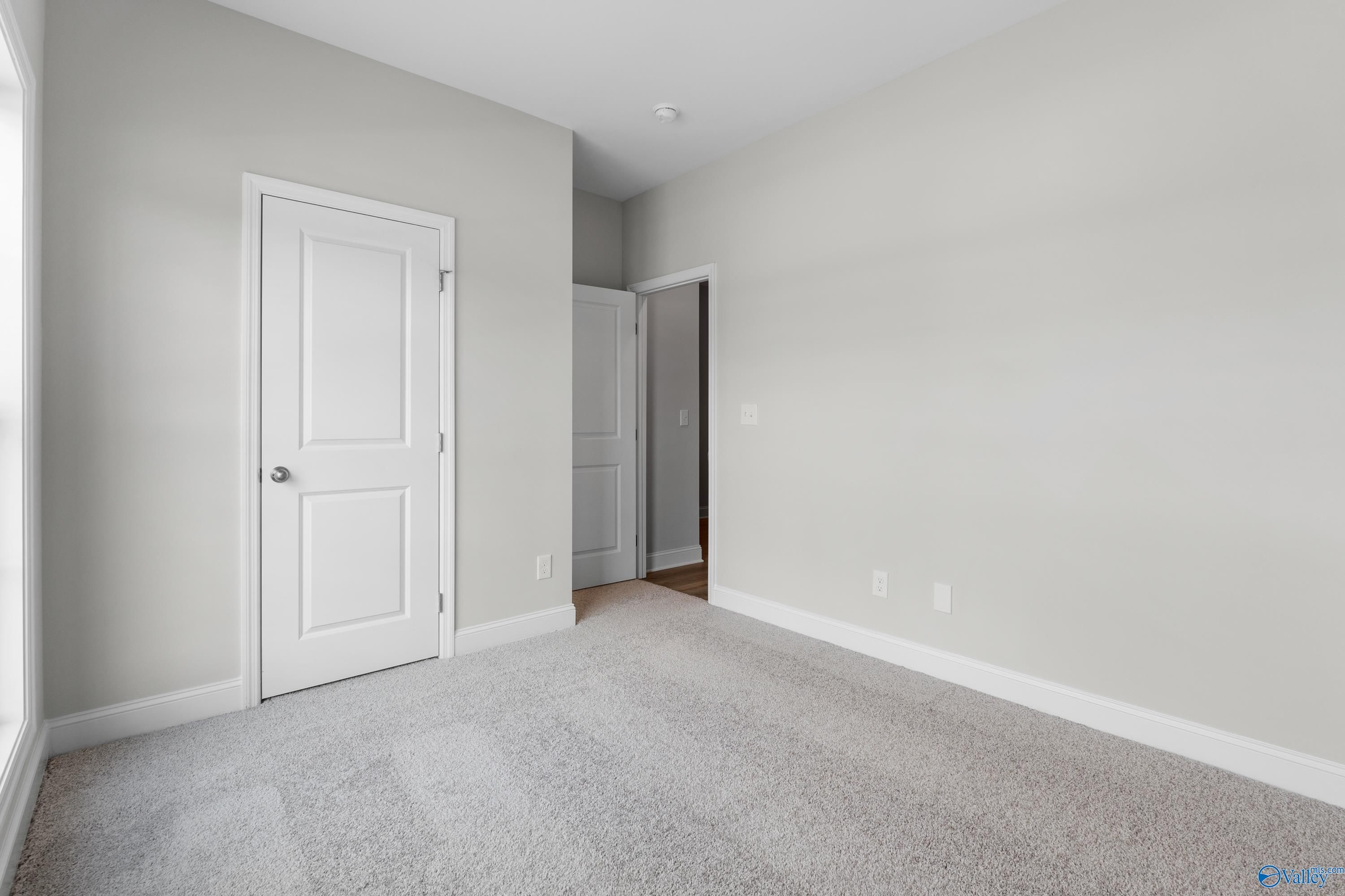 Bright secondary bedroom with gray walls, white doors, carpet flooring, and large window in The Asheville floor plan, Huntsville AL