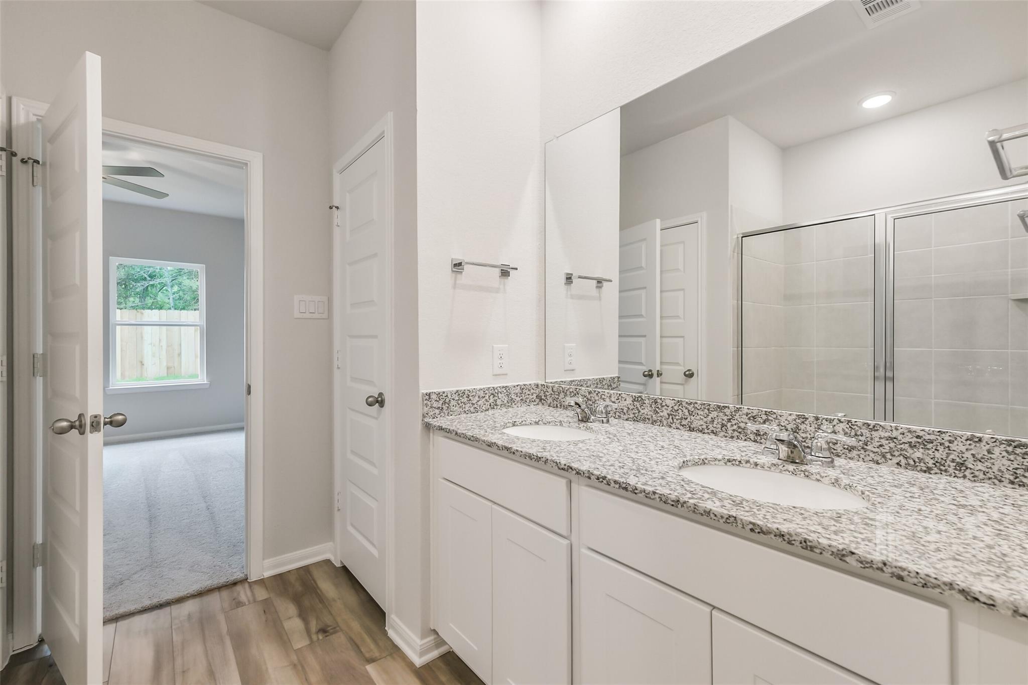 Modern master bathroom with double granite vanity, walk-in shower, white cabinets in Davidson Homes The Brazos F, Conroe, Texas