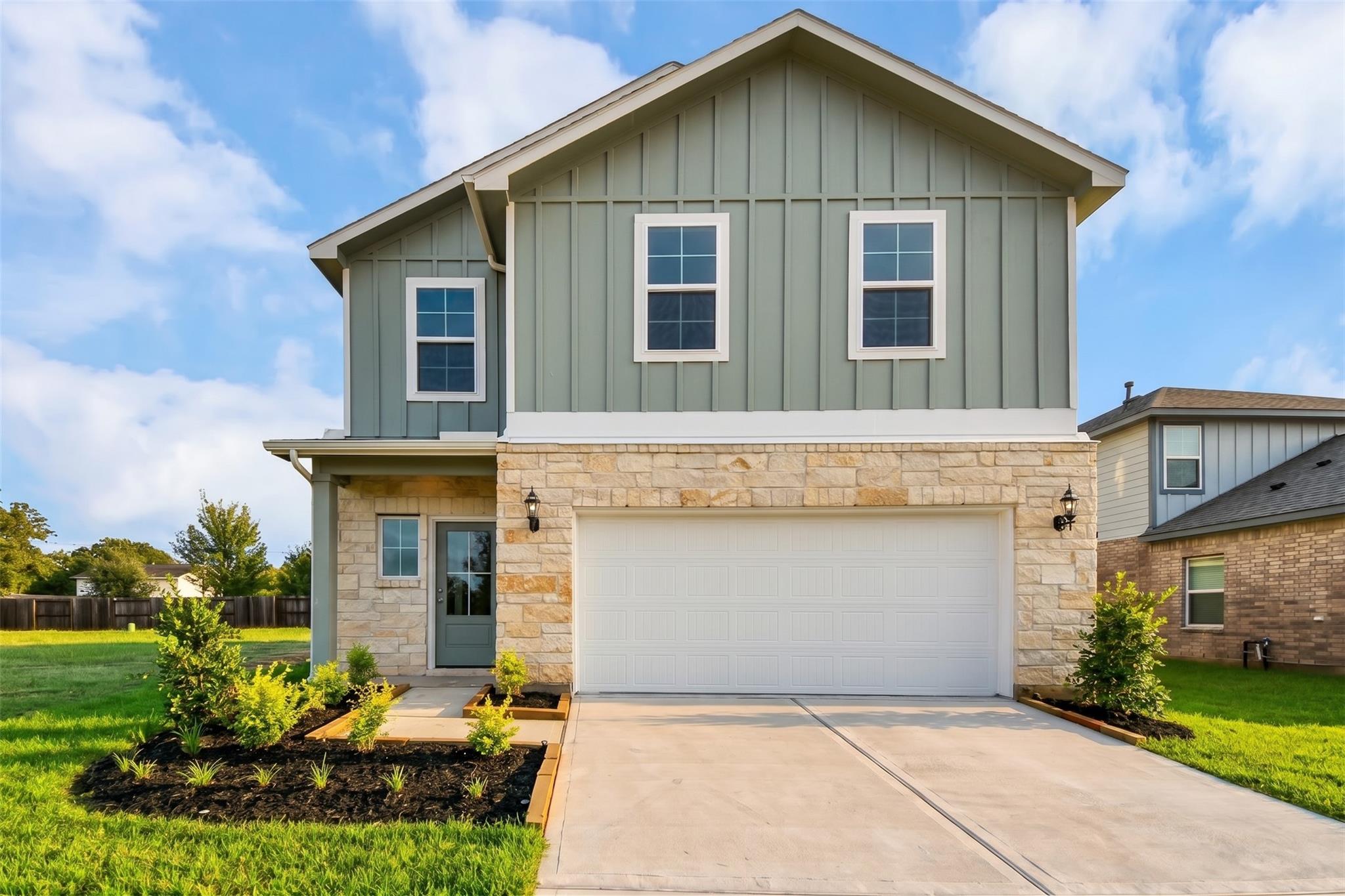 Two-story sage green and stone exterior with 2-car garage at Davidson Homes' The Blanco E in Windmill Estates, Magnolia, Texas