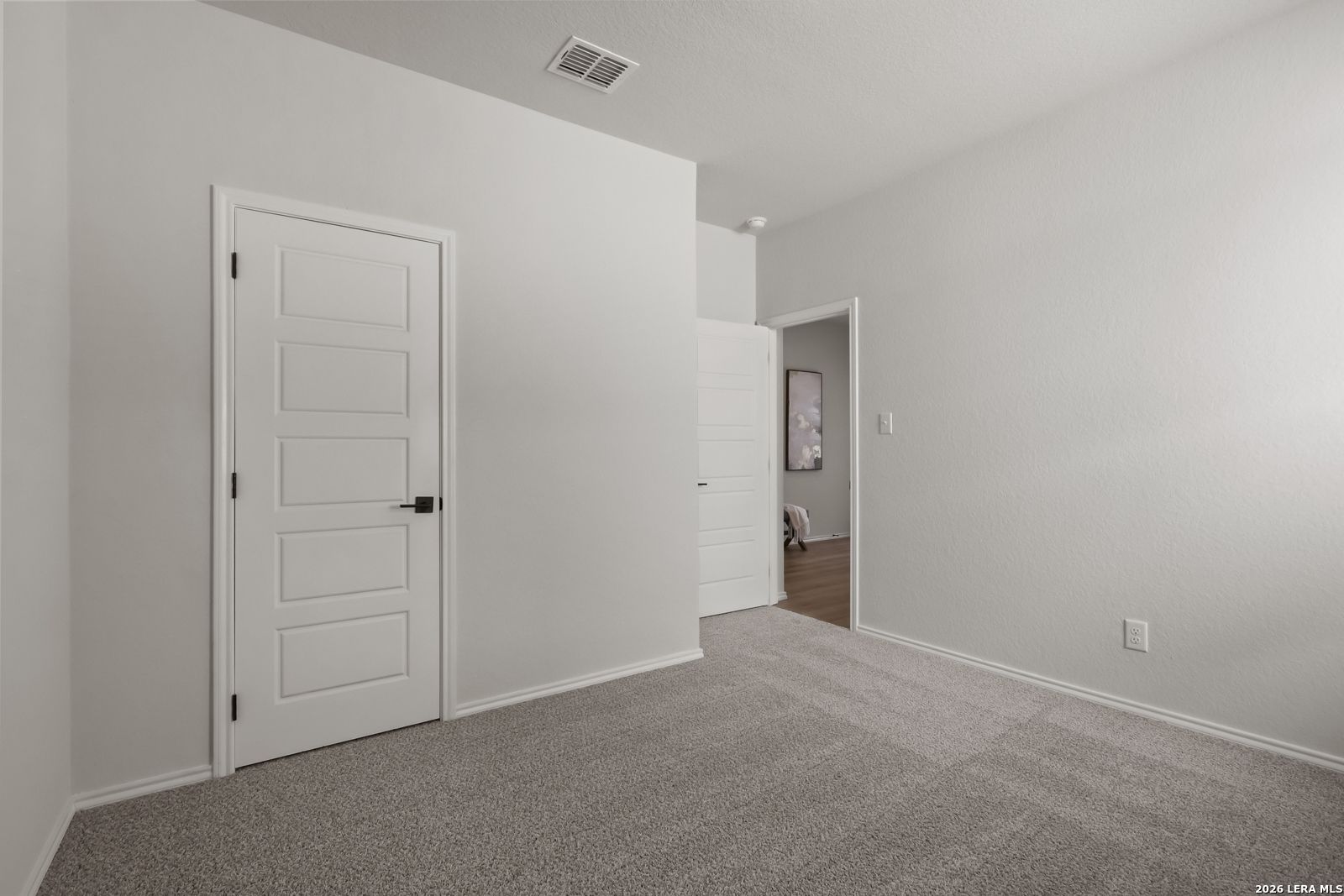 Bright empty secondary bedroom with white walls, carpet floor, and en-suite door in Davidson Homes The Daphne H, Seguin, Texas