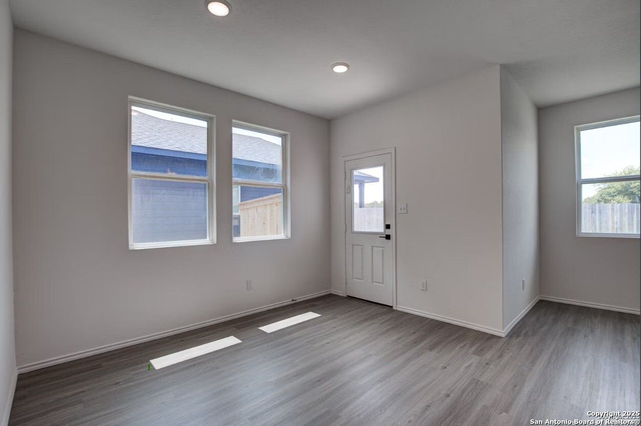 Bright entry living room with large windows, gray LVP flooring, and recessed lighting in The Daphne H home, Seguin, Texas