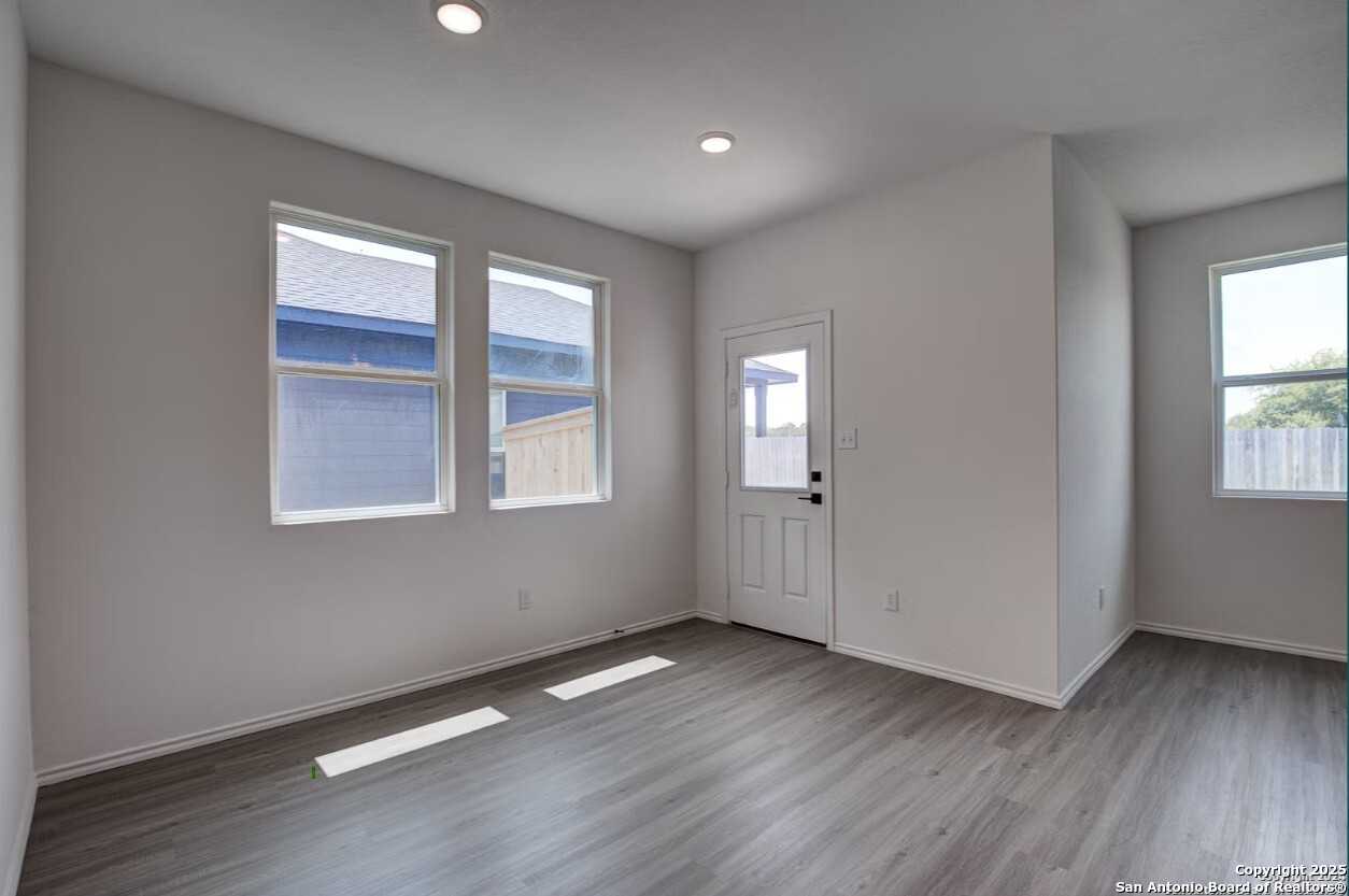 Bright entry living room with large windows, gray LVP flooring, and recessed lighting in The Daphne H home, Seguin, Texas
