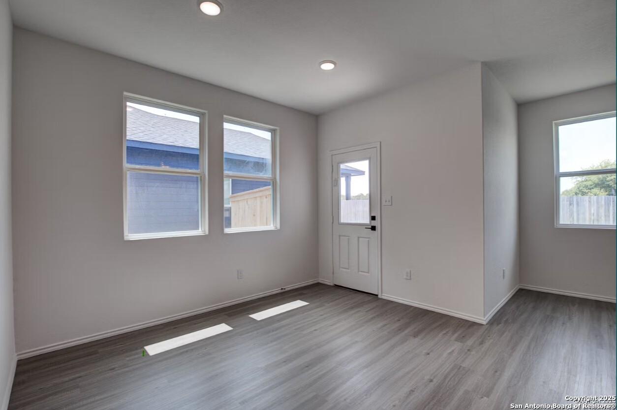 Bright entry living room with large windows, gray LVP flooring, and recessed lighting in The Daphne H home, Seguin, Texas
