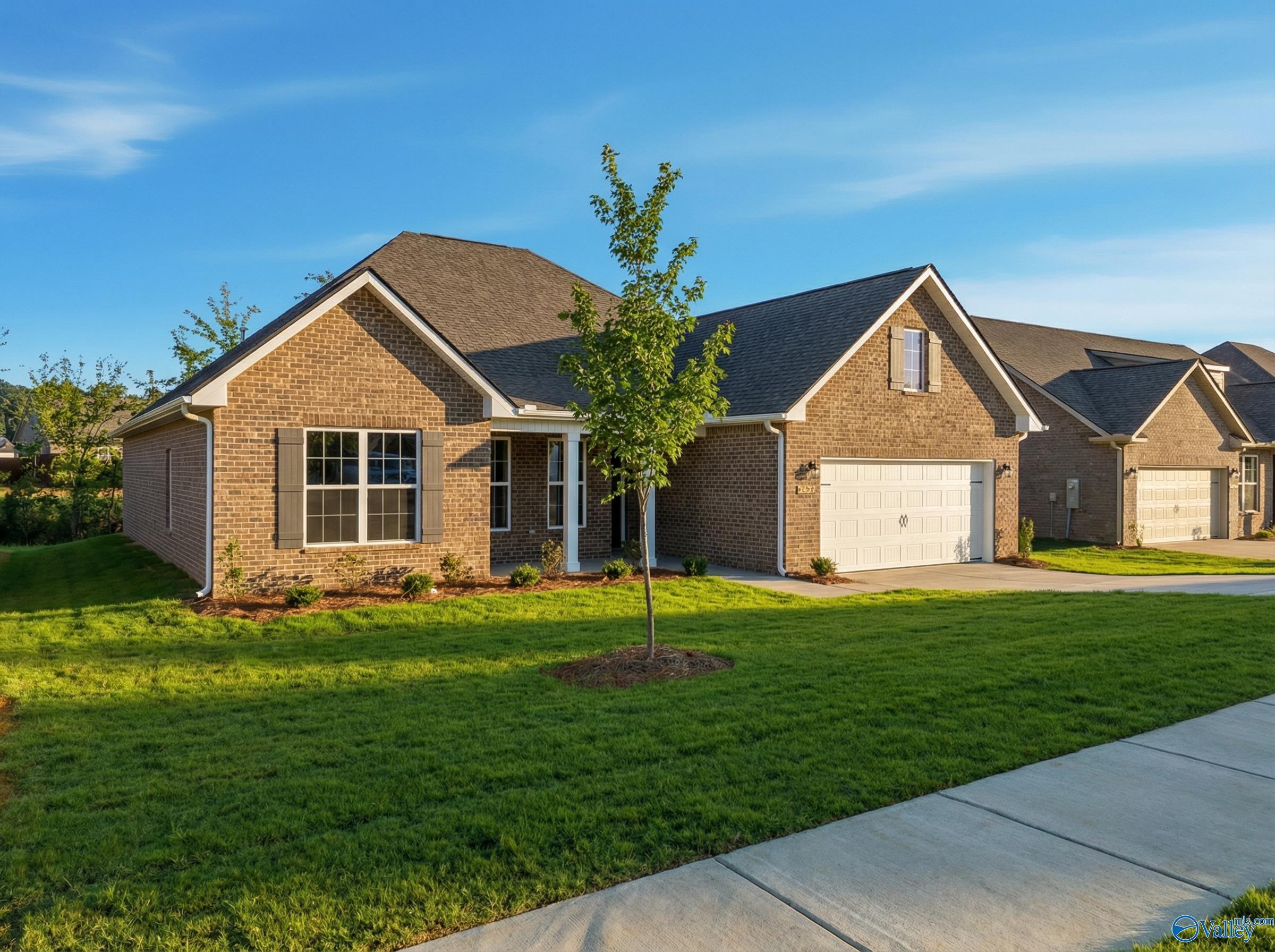 Brick 1-story Rockford home by Davidson Homes with 2-car garage, young tree, and lush lawn in Creekside, Harvest, Alabama