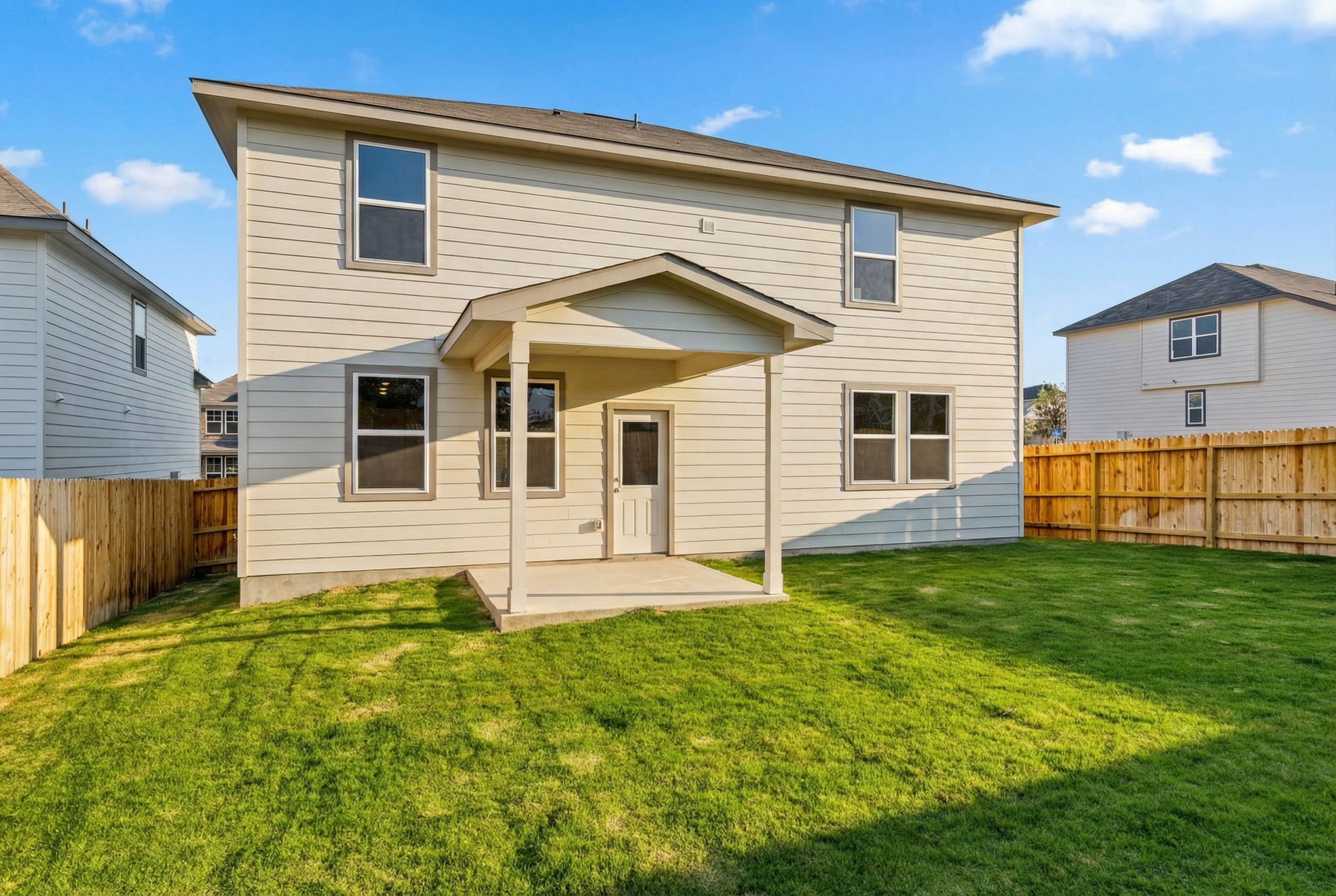 Rear view of two-story Douglas F home with covered patio, fenced grassy yard in Royal Crest, San Antonio, Texas by Davidson Homes
