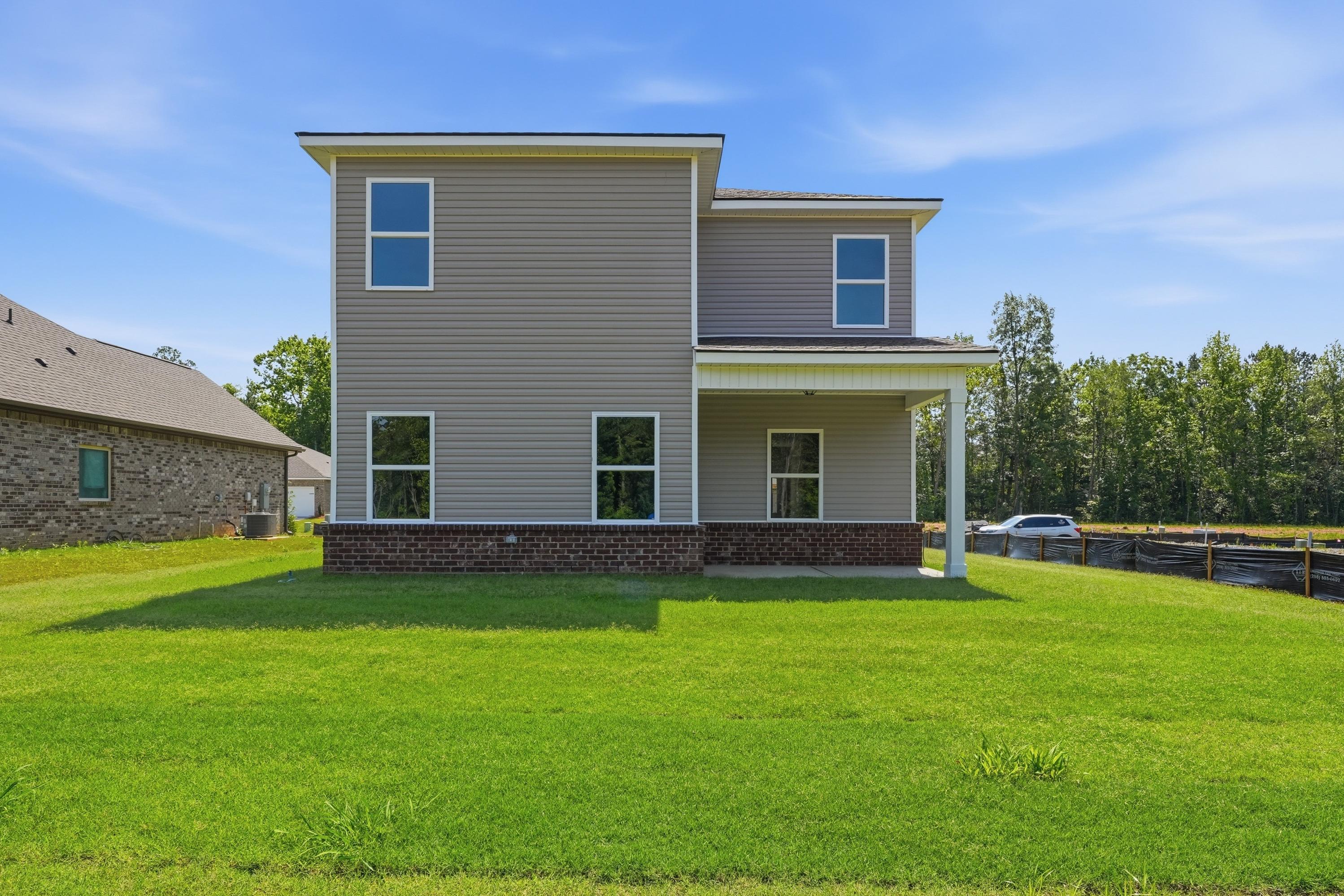 Rear exterior view of The Russell A single-family home featuring a two-story design, brick base, and spacious backyard.