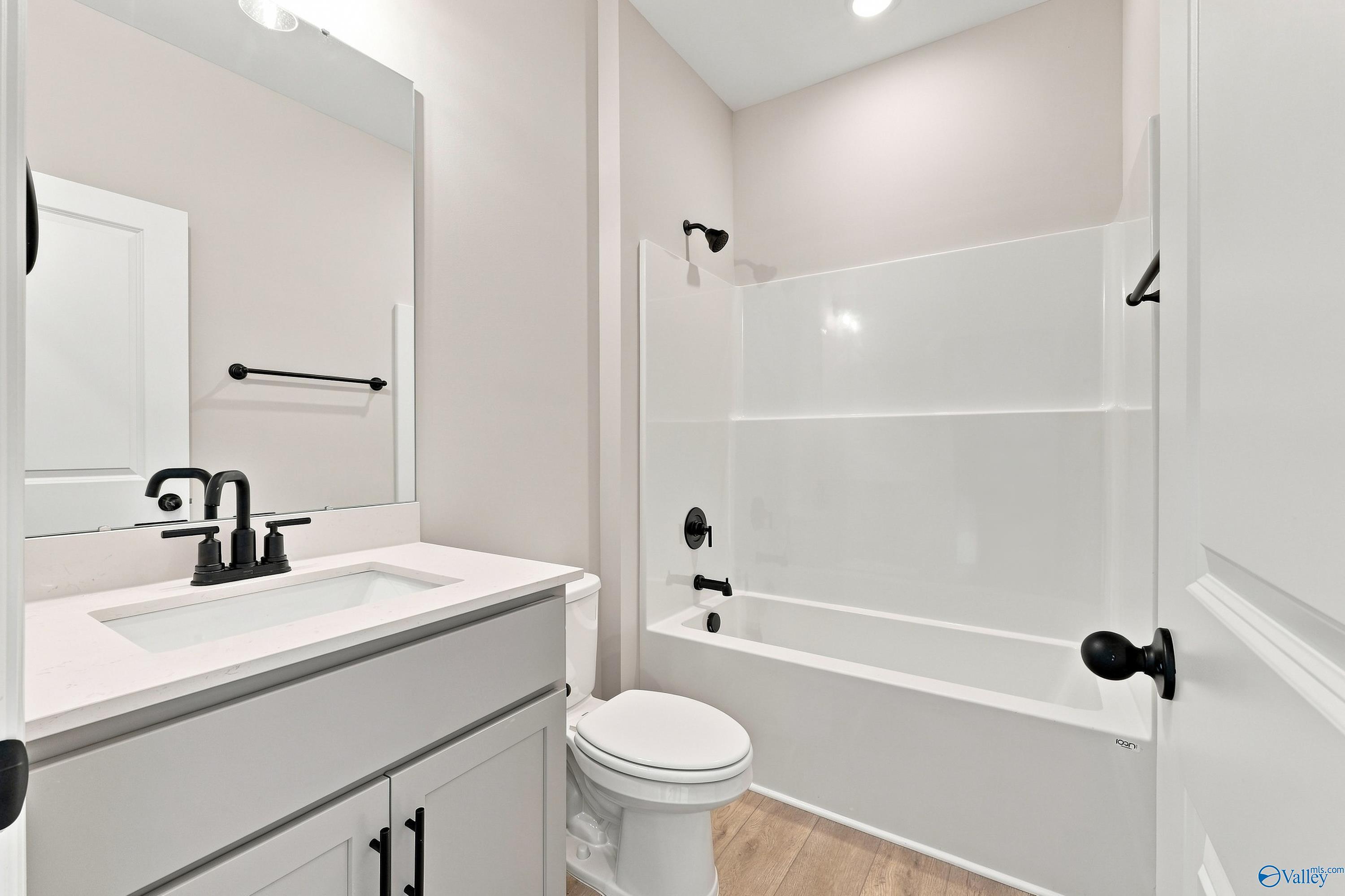 Modern bathroom with white vanity, matte black fixtures, and tub-shower combo in Davidson Homes Montgomery D, Athens, AL