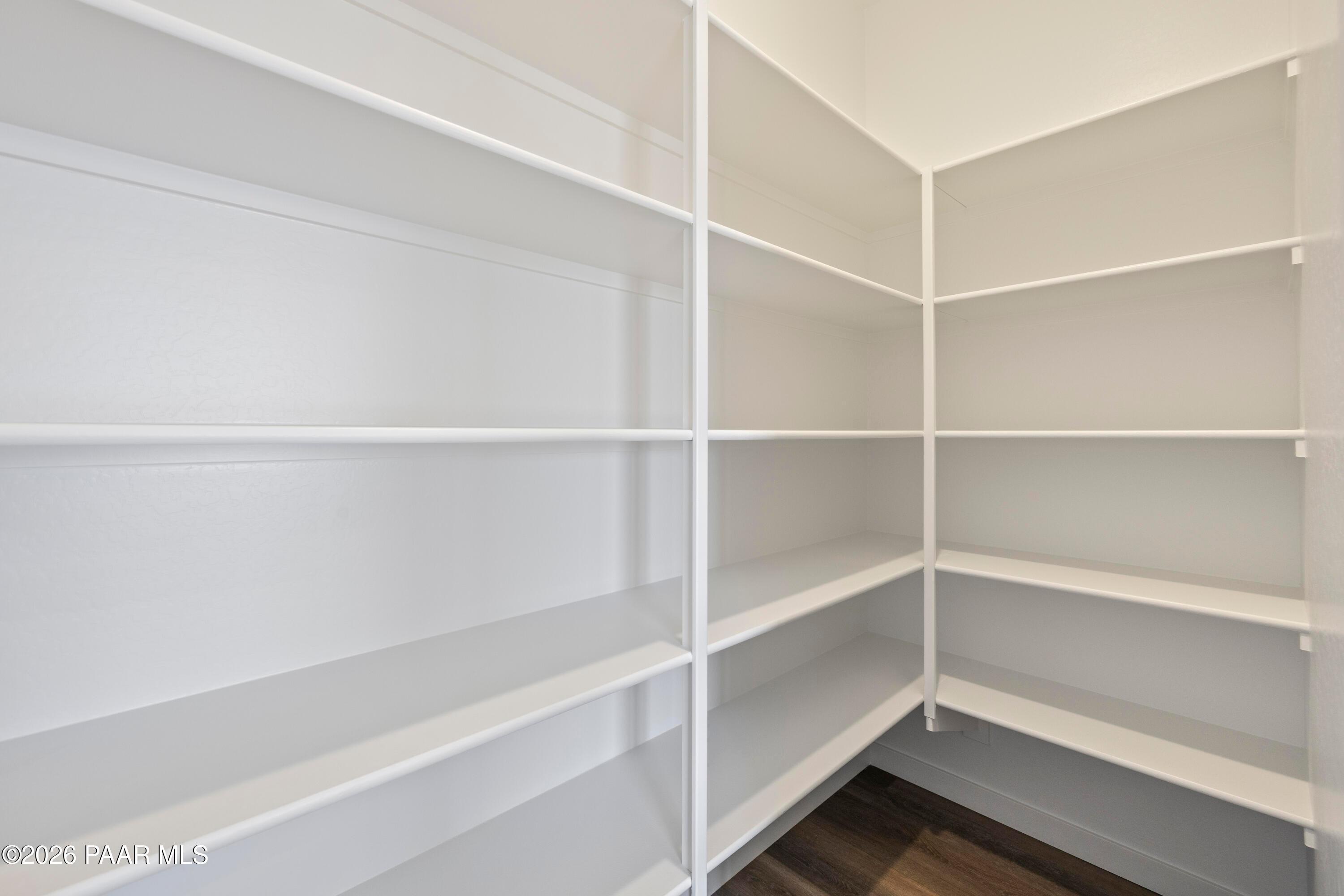 Spacious walk-in closet with white corner shelving and hardwood floors in Davidson Homes The Soleil E, Prescott, Arizona