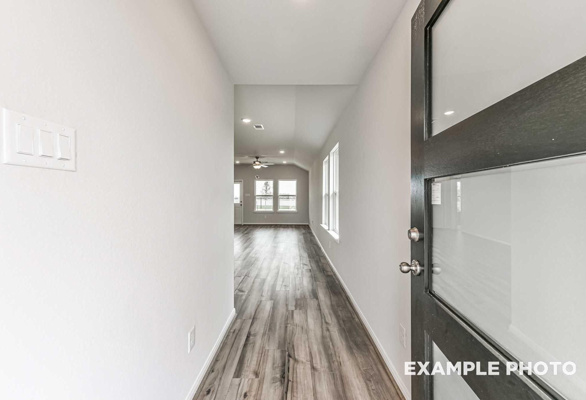 Entryway and hallway of The Azure home with luxury vinyl plank flooring, glass-panel front door, and bright open living space