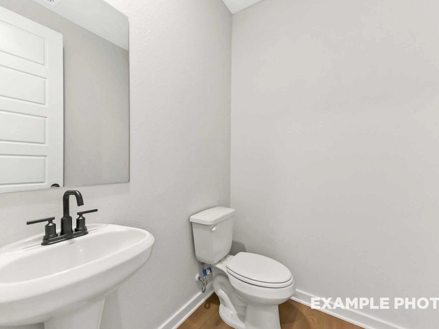 Modern half-bath with pedestal sink and matte black fixtures in The Sequoia C floor plan at Sundance Cove, Crosby, Texas.