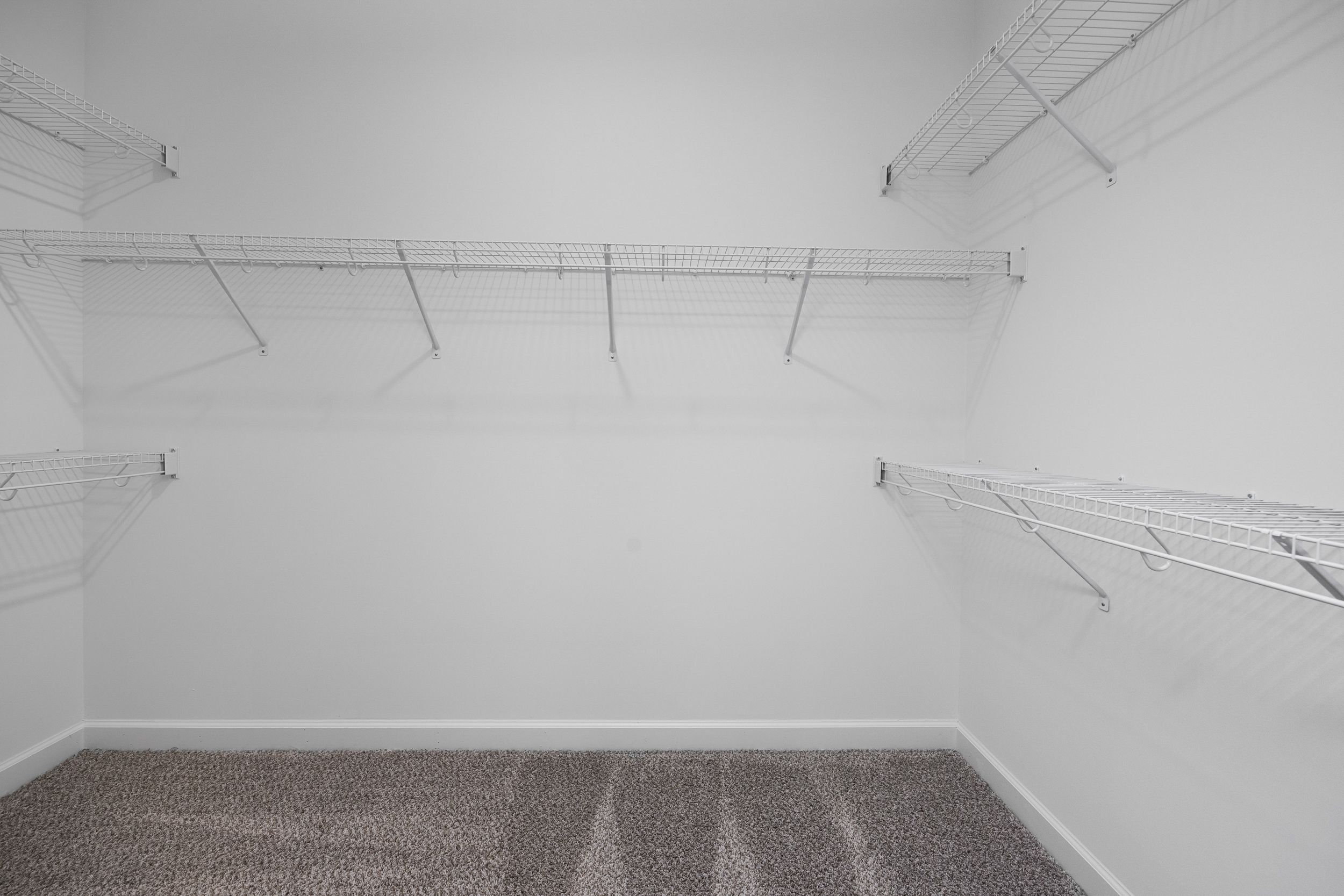 Spacious master walk-in closet in The Magnolia B with white walls, wire shelving, and neutral carpet floor