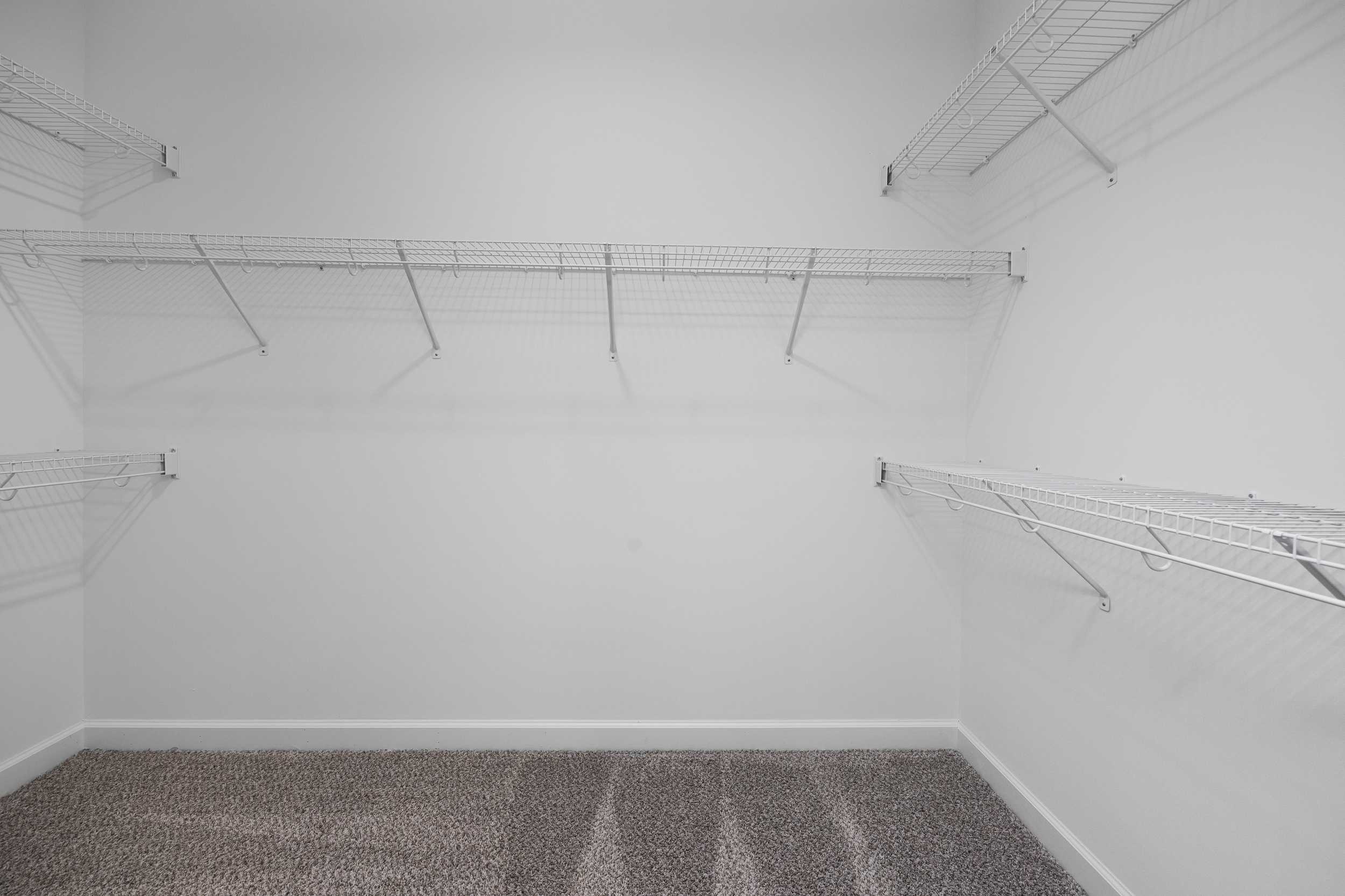 Spacious walk-in closet in The Magnolia A with wire shelving, white walls, and carpeted floor