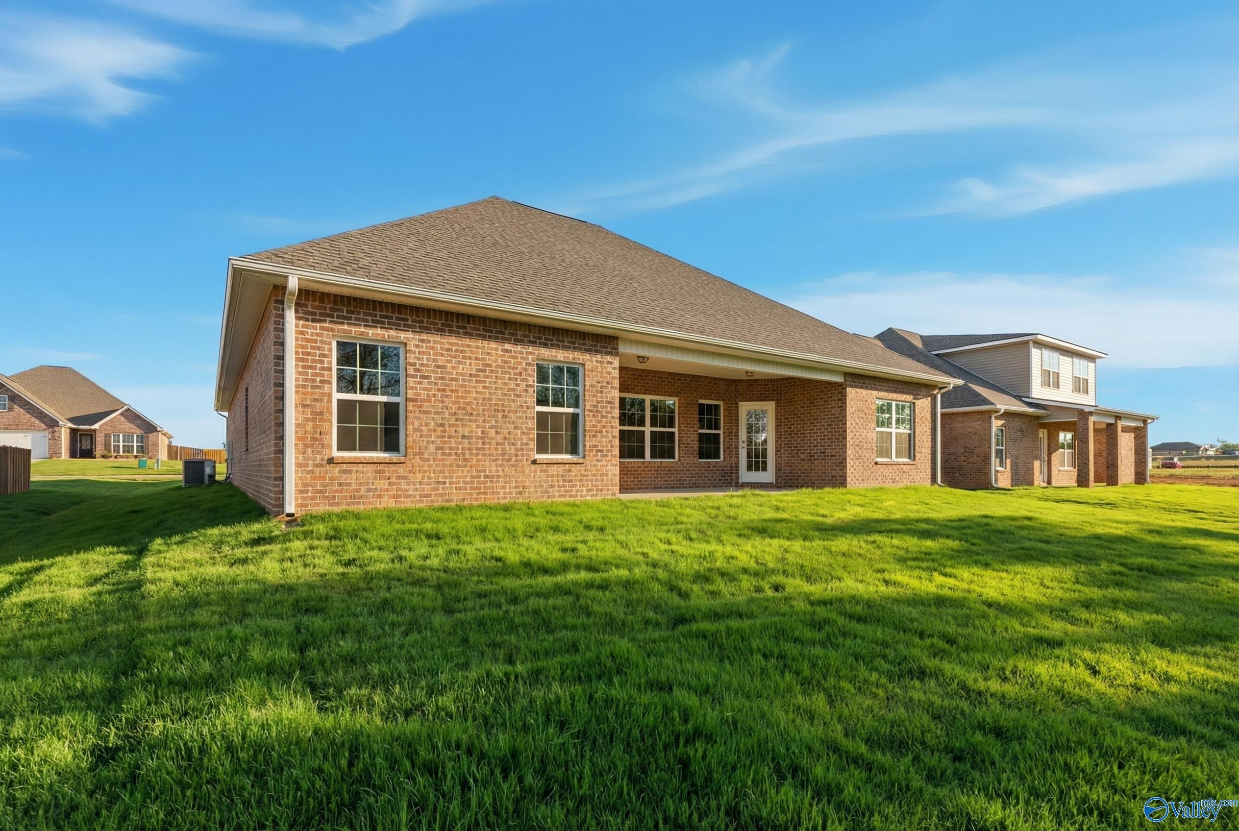 Brick exterior of Davidson Homes The Rockford with covered patio, large windows, and lush green yard in Creekside, Harvest, Alabama