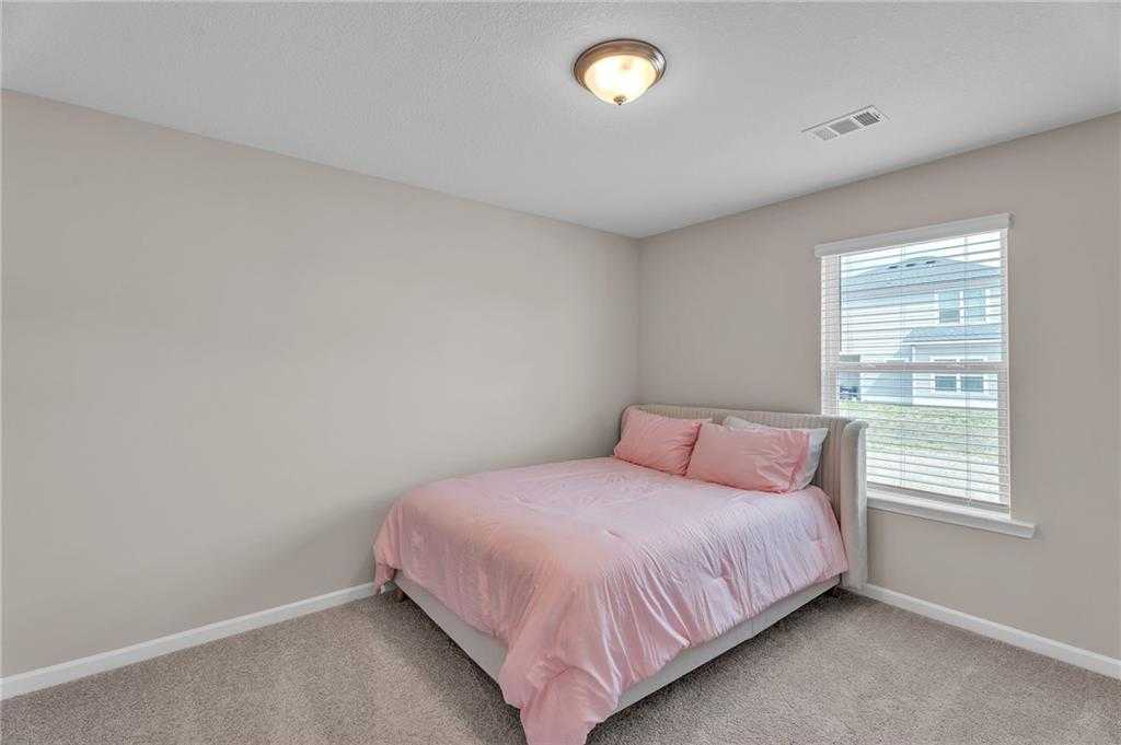 Cozy bedroom with pink bedding, beige walls, and window blinds in Davidson Homes The Bartlett, Phenix City, Alabama