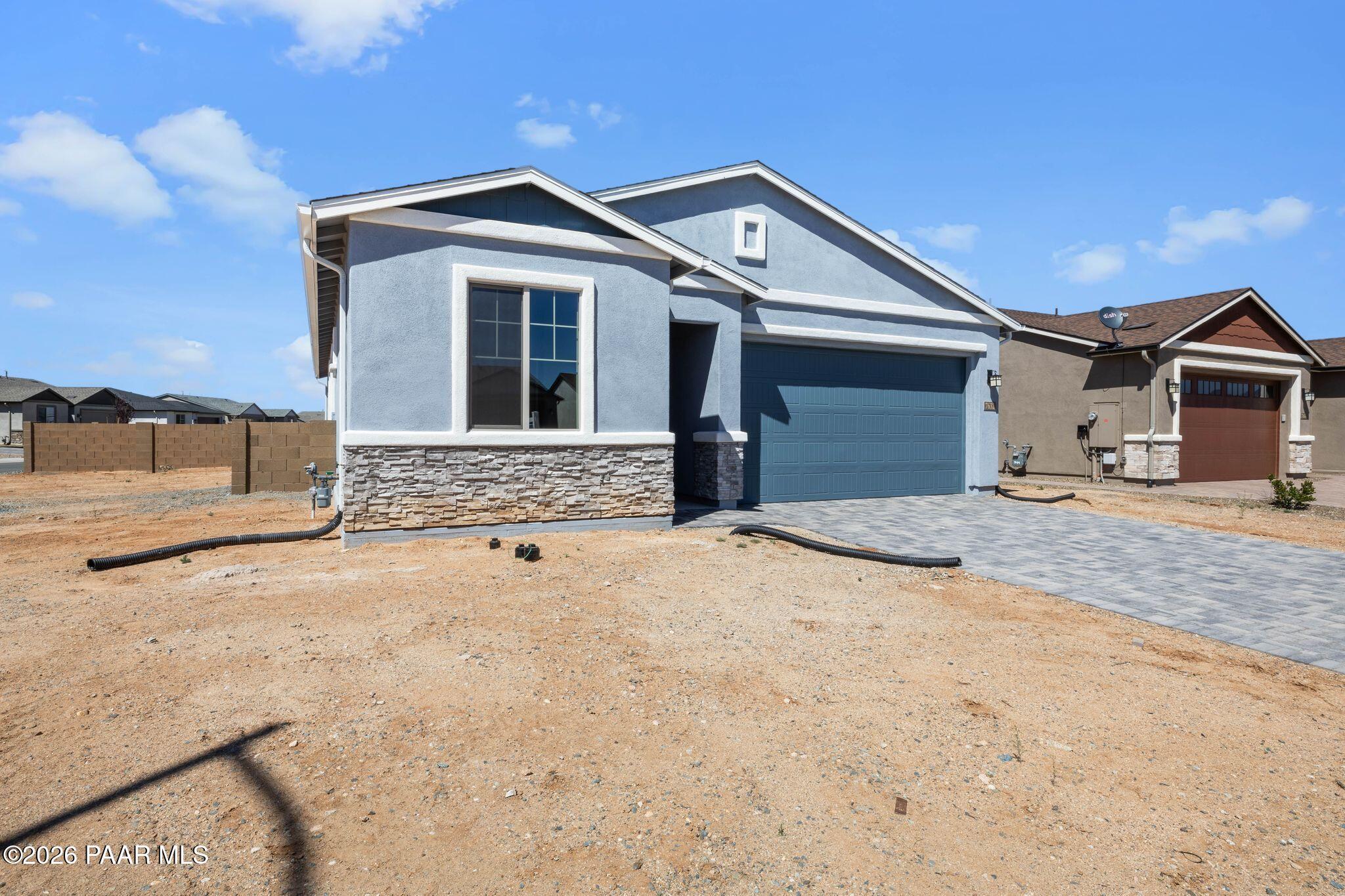 Modern blue single-story home with 3-car garage, stone accents, and paver driveway in North Ridge at Pronghorn Ranch, Prescott Valley, Arizona