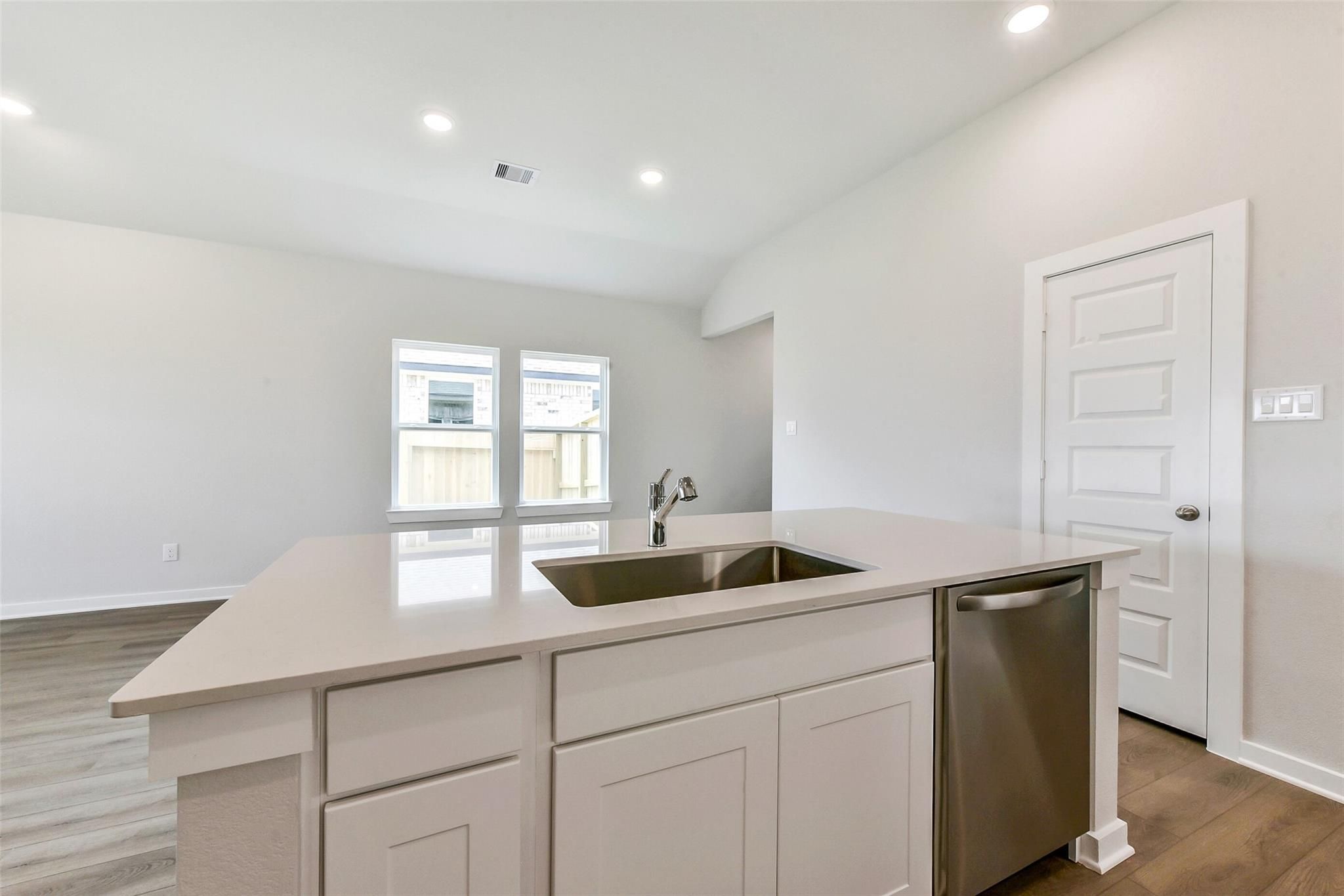 Modern kitchen island with quartz countertop, stainless sink and dishwasher in Davidson Homes The Costa B, Dayton, Texas