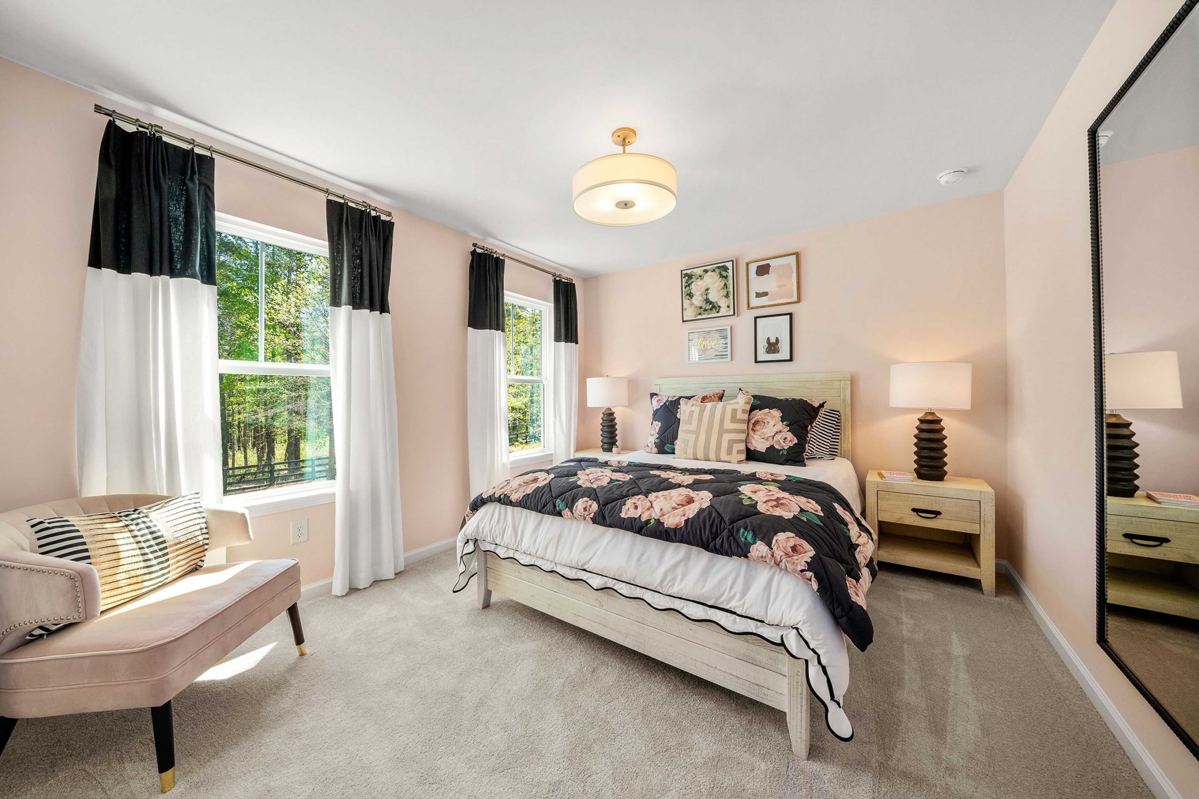 Spacious primary bedroom at Riverwood in Dallas Georgia with king floral bed, chandelier, pink walls, and large windows