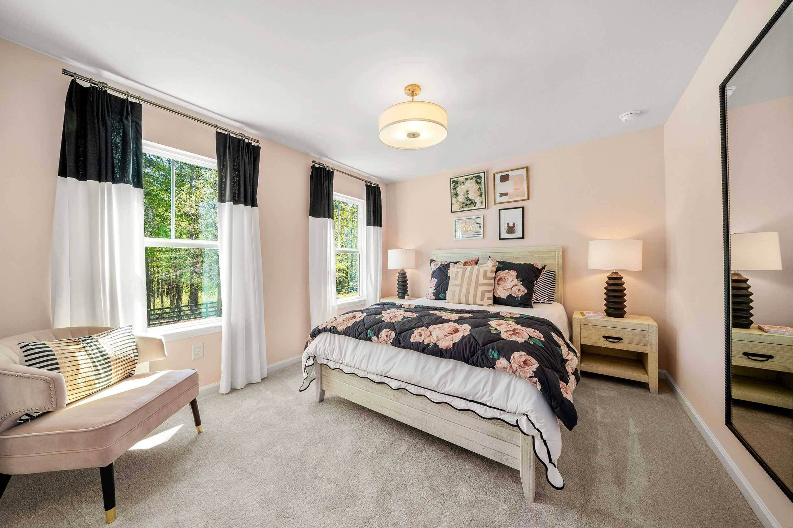 Spacious primary bedroom at Riverwood in Dallas Georgia with king floral bed, chandelier, pink walls, and large windows