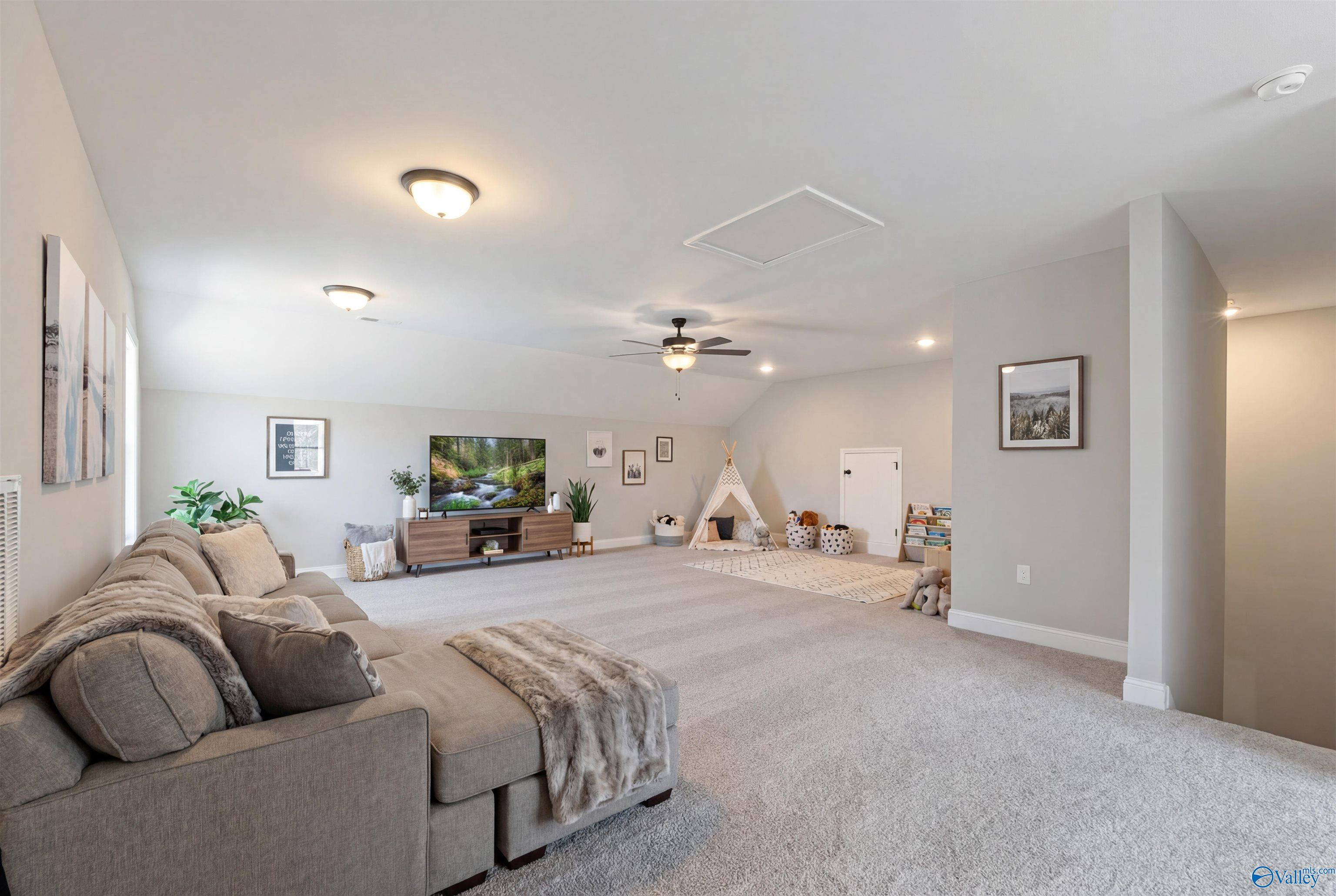 Cozy bonus room featuring sectional sofa, TV entertainment center, kids' teepee play area, plants, and ceiling fan in Davidson Homes The Rockford with Bonus, Toney, Alabama