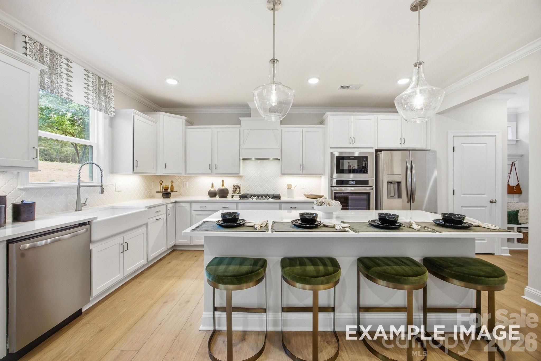 Modern kitchen with white cabinets, island seating, and stainless appliances in Hickory B II floor plan, Mooresville, NC.