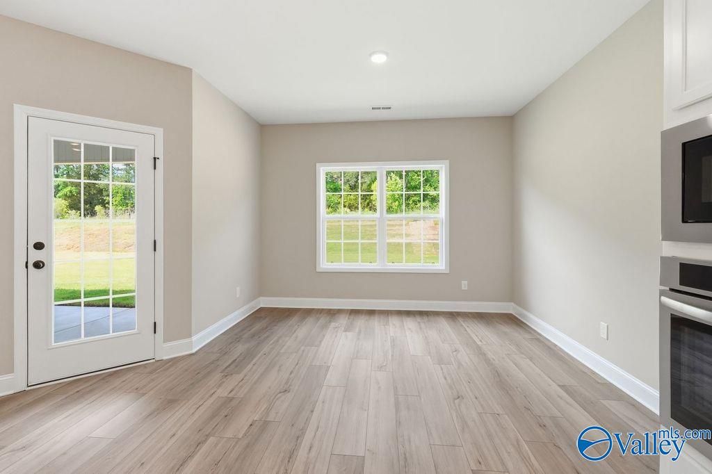 Bright dining area with wood-look flooring and glass door in The Rockford floor plan at Cain Park, Hartselle, Alabama.