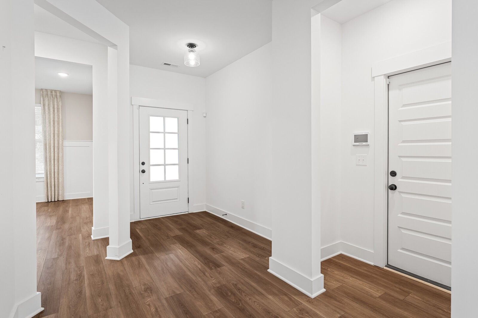 Bright entry foyer with hardwood floors, glass-paneled front door, and arched columns in Davidson Homes The Ridgeport, Gallatin, TN