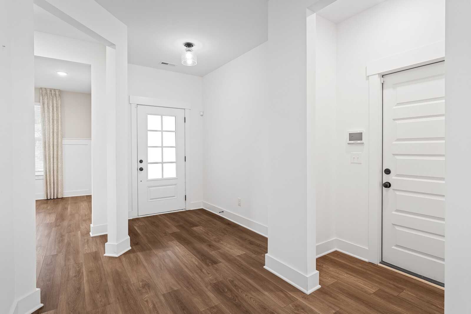 Bright entry foyer with hardwood floors, glass-paneled front door, and arched columns in Davidson Homes The Ridgeport, Gallatin, TN