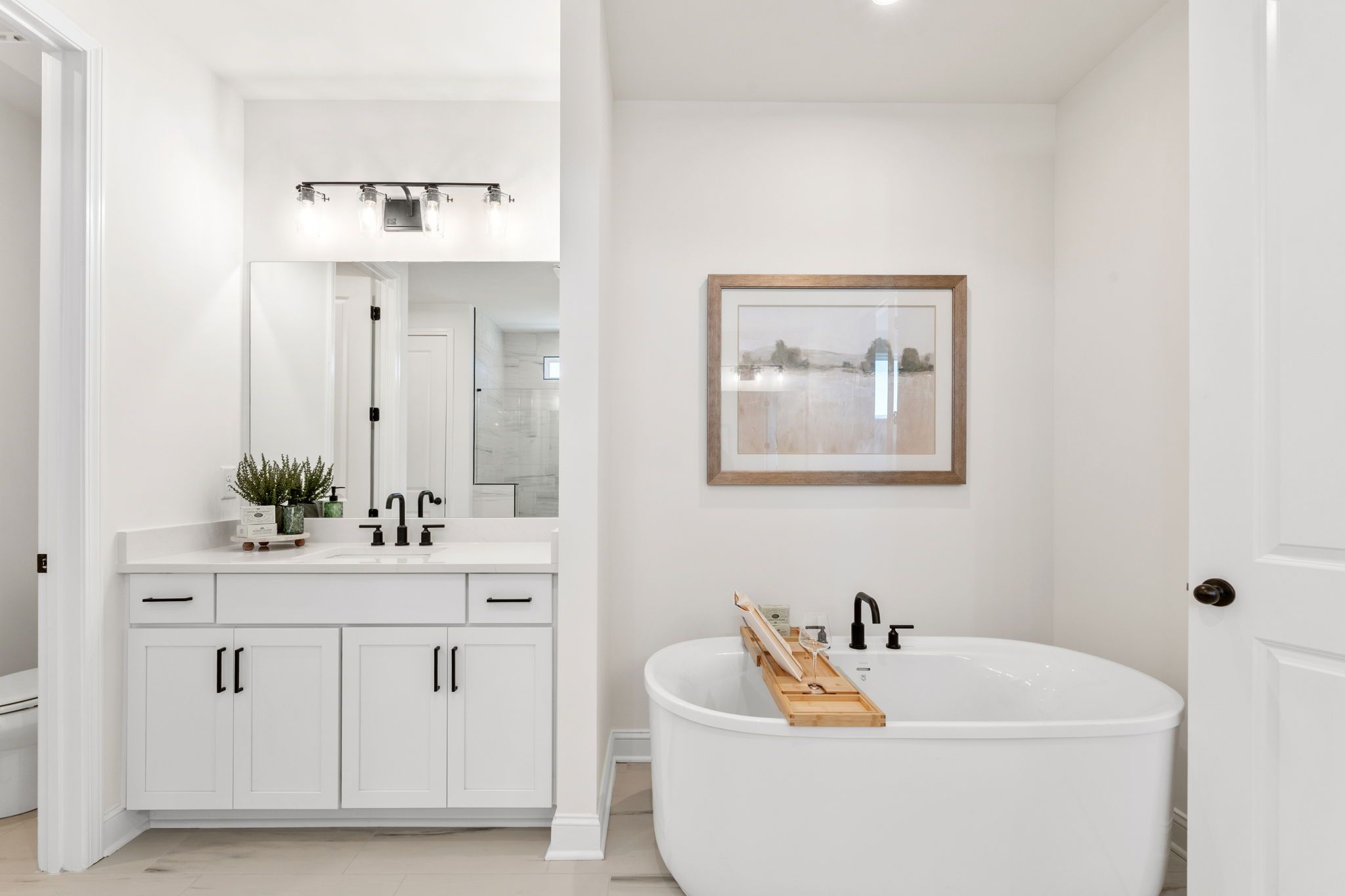 Spacious white master bathroom at Fern Hollow in Buford GA with freestanding tub, double vanity, and modern fixtures