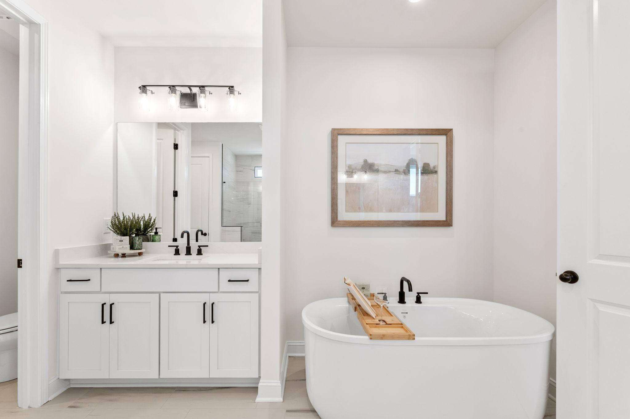 Spacious white master bathroom at Fern Hollow in Buford GA with freestanding tub, double vanity, and modern fixtures