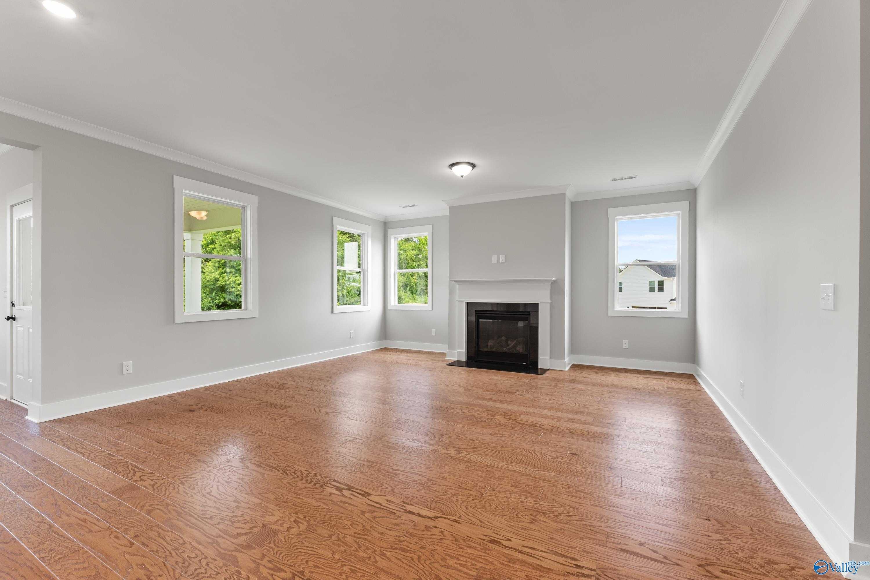 Bright living room with gas fireplace, hardwood floors, and large windows in Davidson Homes The Arcadia, Huntsville AL