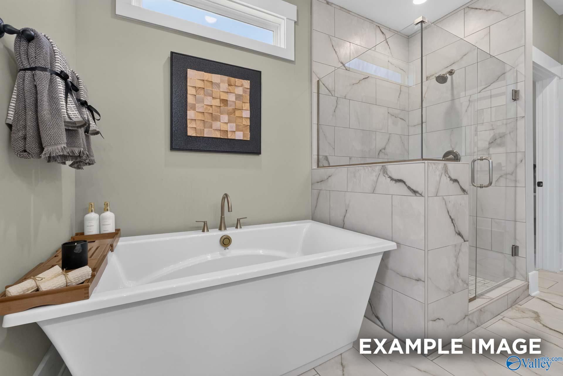 Freestanding soaking tub with marble tile walk-in shower in master bath of Davidson Homes Ashport K, Hazel Green, Alabama