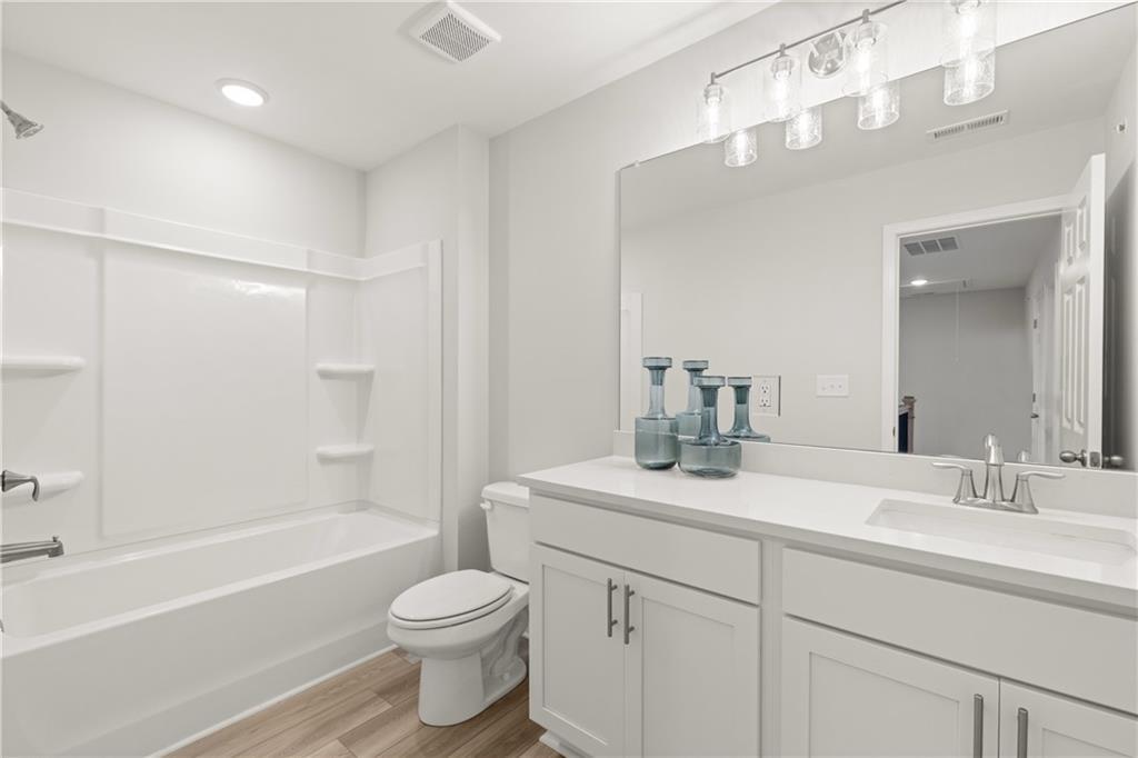 Modern bathroom with white vanity, tub-shower combo, and large mirror in The Wake B plan by Davidson Homes in Cumming, GA.