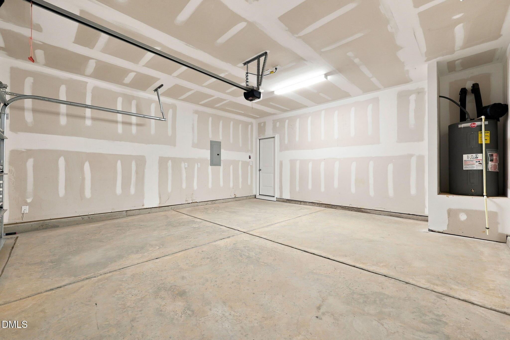 Unfinished 2-car garage with drywall and water heater in The Magnolia B floor plan at Retreat at North Main, Lillington, NC.