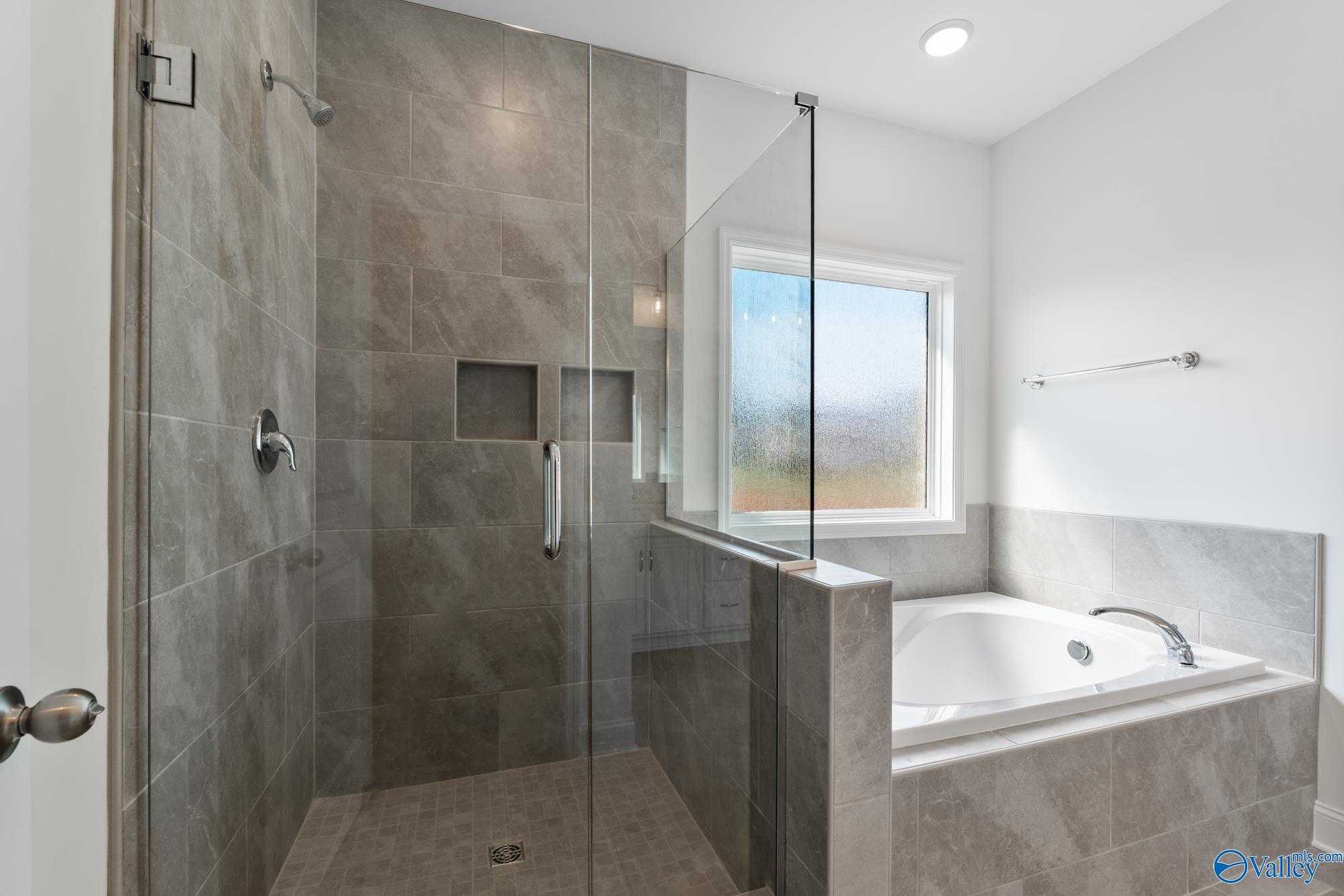 Modern master bathroom with frameless glass shower, soaking tub, and tiled accents in Davidson Homes The Harrison, Meridianville, Alabama