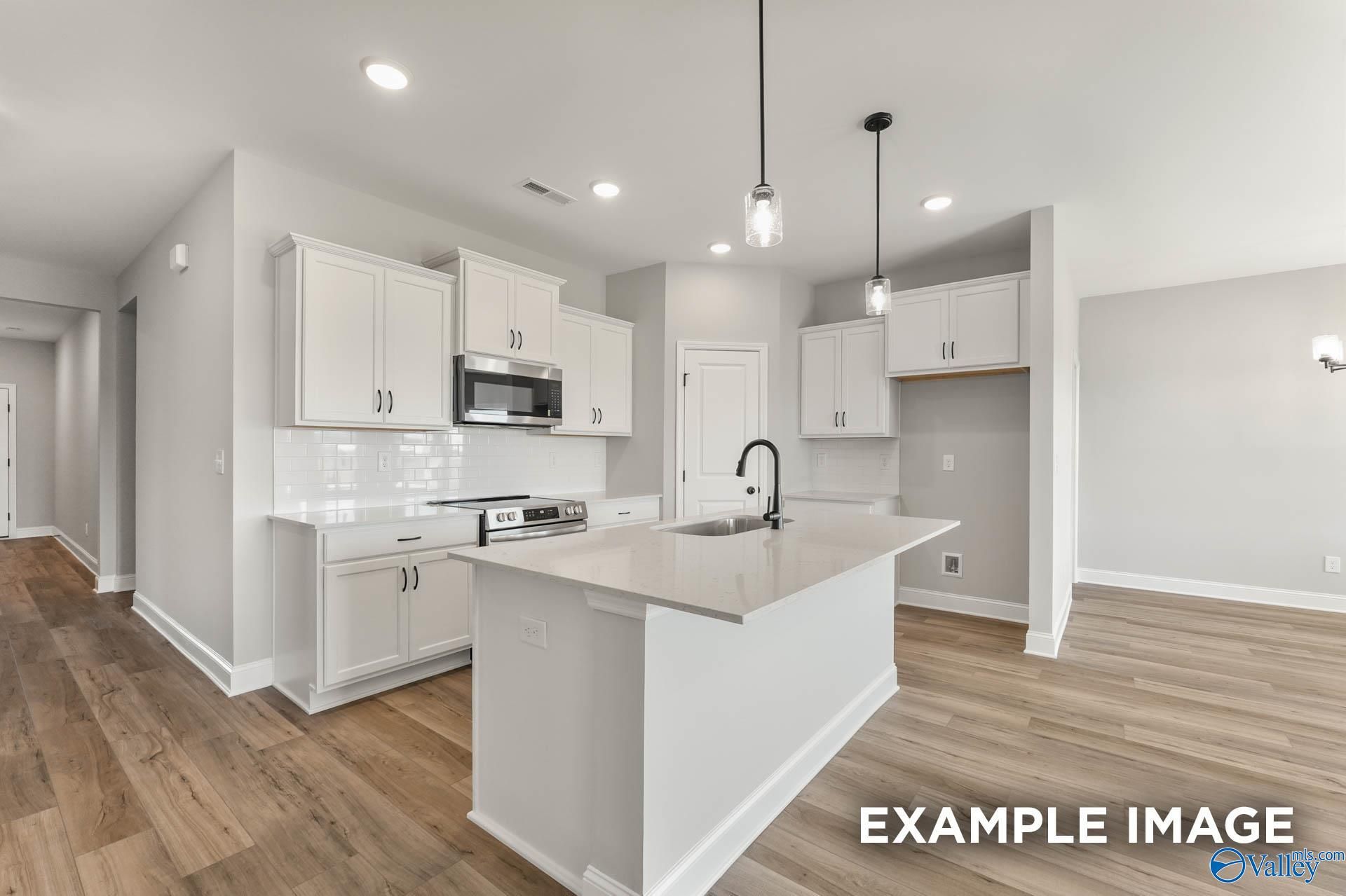 Bright open-concept kitchen with white shaker cabinets, quartz island sink, stainless appliances in Davidson Homes Daphne C, Athens AL