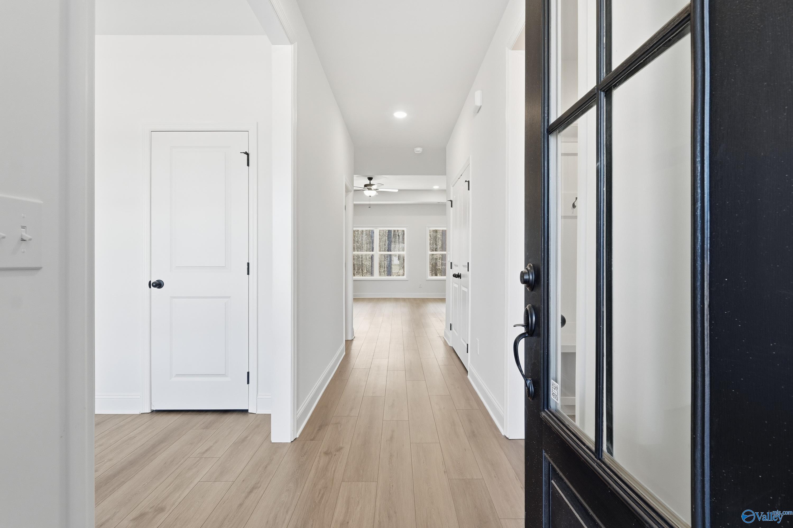 Bright hallway with light oak floors, white walls, and black front door in Davidson Homes The Rockford D, Hazel Green, AL