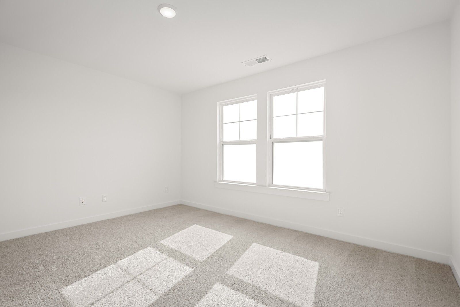 Bright empty bedroom with large windows, white walls, and beige carpet in Davidson Homes The Logan C, Gallatin, Tennessee