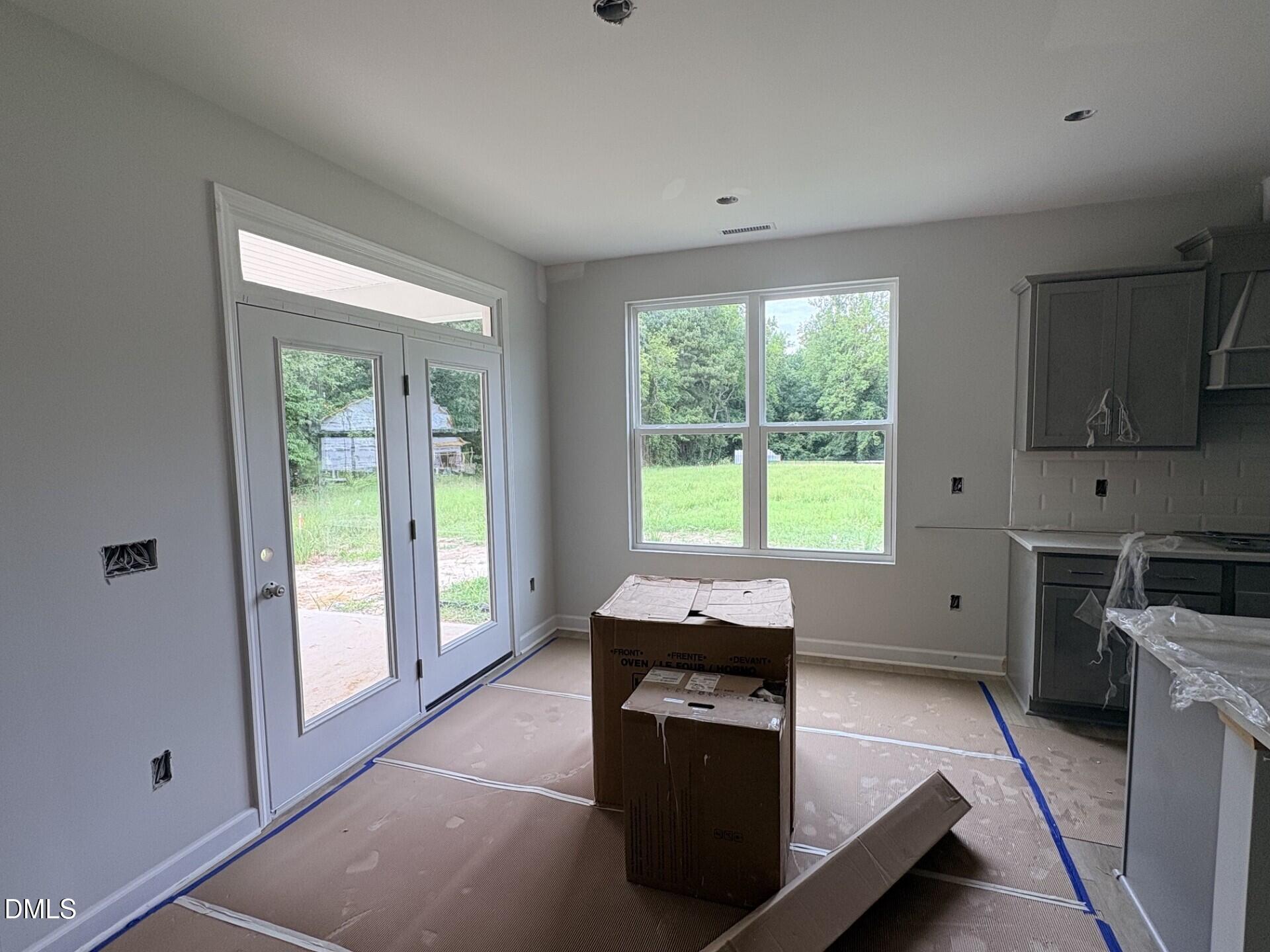 Bright breakfast nook with double glass doors and gray kitchen cabinetry in The Ash C floor plan, Woodland Crossing, Zebulon.