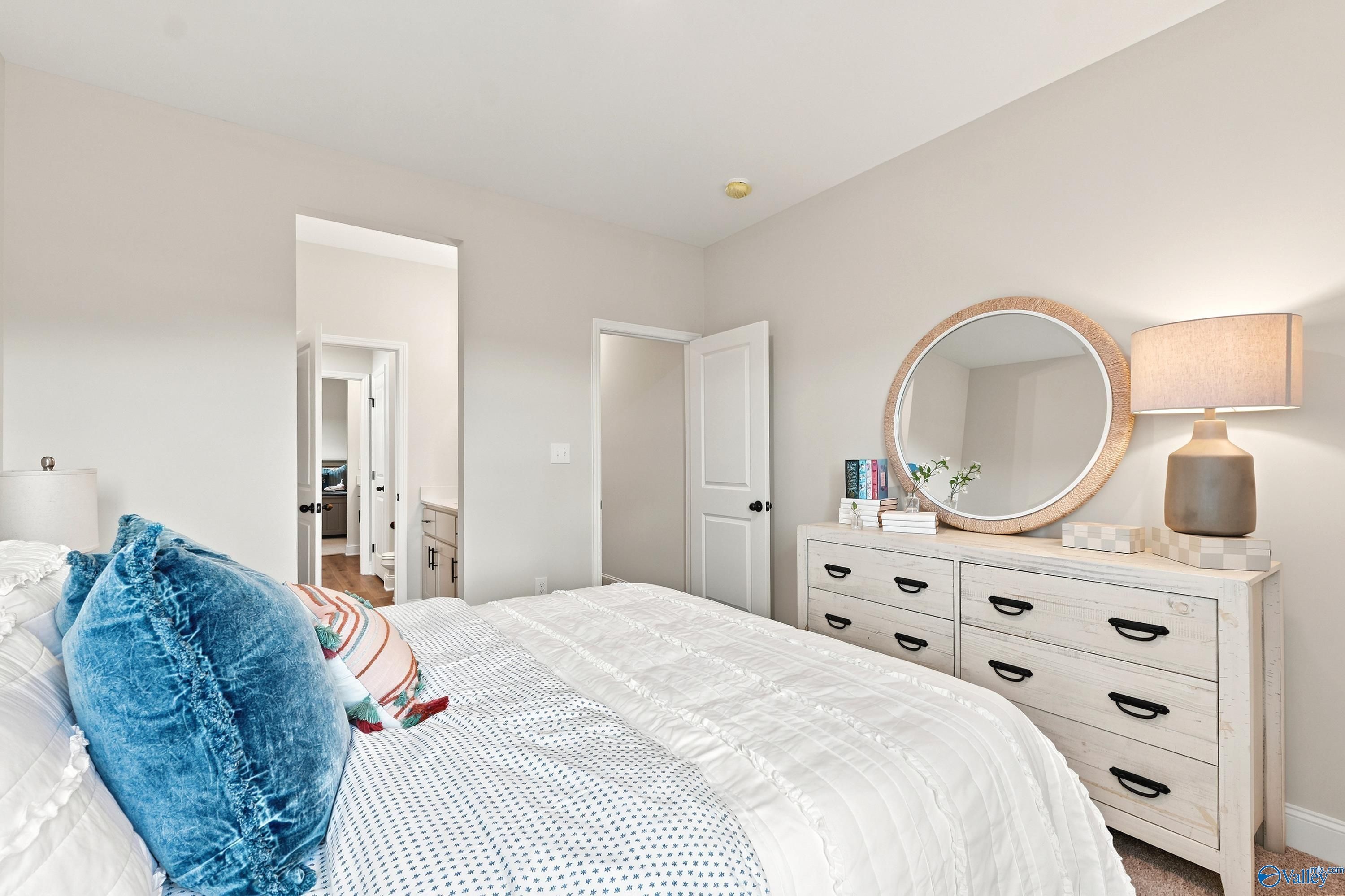 Cozy bedroom with white dresser and round mirror in The Finleigh floor plan at Riverton Preserve, Huntsville, Alabama.