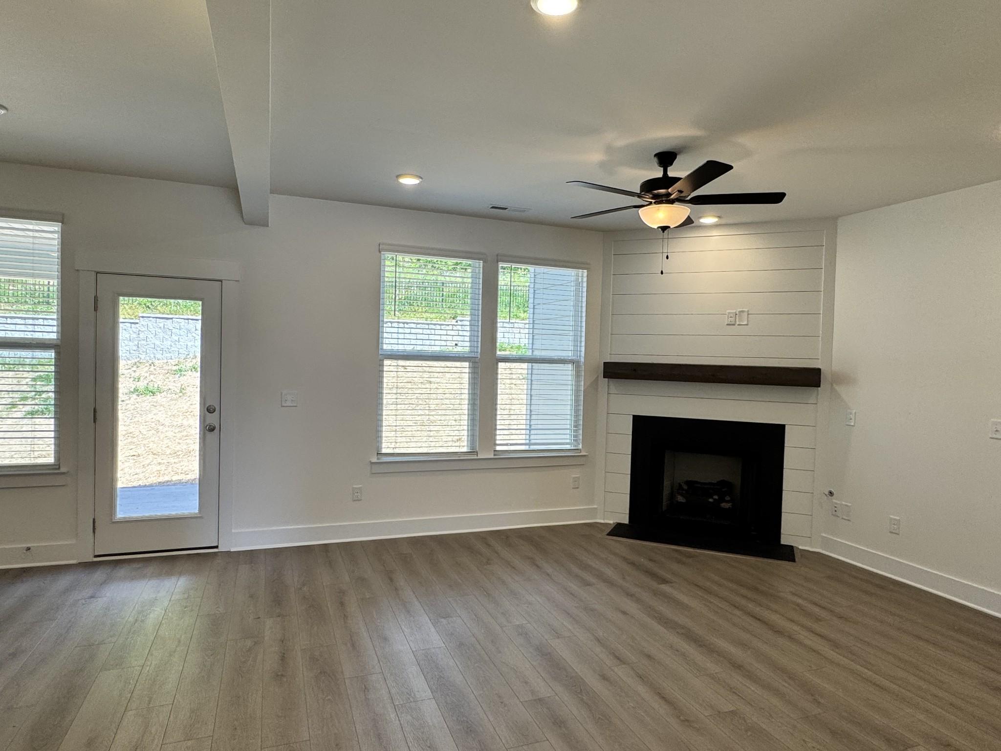 Spacious family room with shiplap fireplace, ceiling fan, hardwood floors and sliding door in Davidson Homes The Willow, Gallatin TN