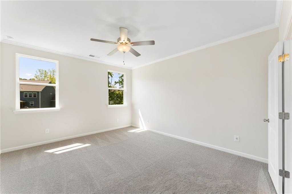 Bright secondary bedroom with beige walls, gray carpet, ceiling fan, and large windows in Davidson Homes The Ash B, Riverwood, GA