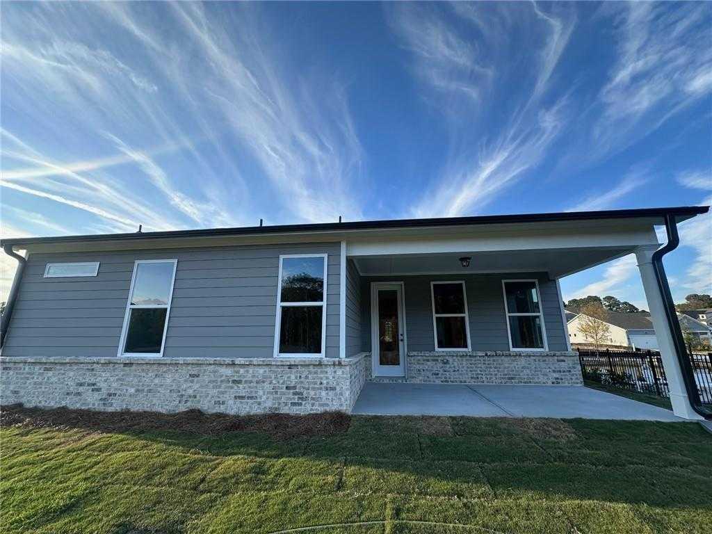 Modern 1-story Glenwood C home exterior with gray siding, covered front porch, large windows, brick base, and green lawn in Kelly Preserve, Loganville, GA