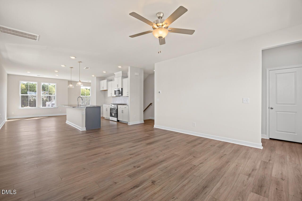 Open-concept living area with luxury vinyl plank floors, white kitchen, and island in Davidson Homes Mitchell plan, Knightdale NC