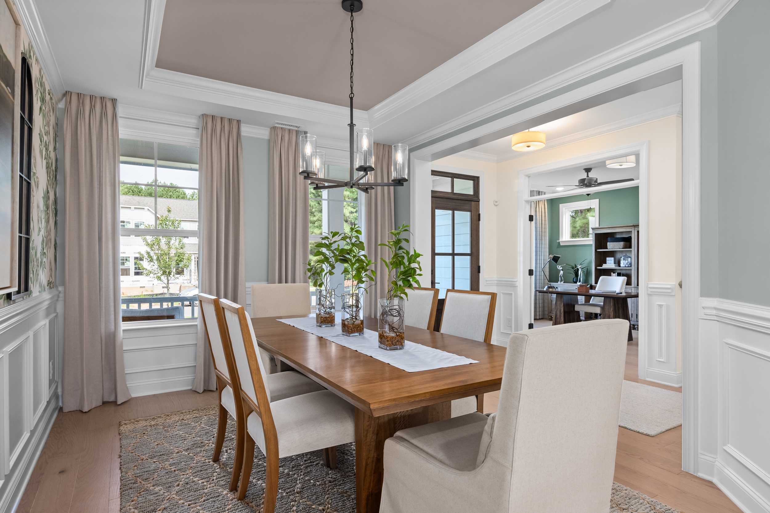 Elegant dining room at Laneridge Estates in Raleigh NC featuring wooden table, beige chairs, chandelier, and open study view
