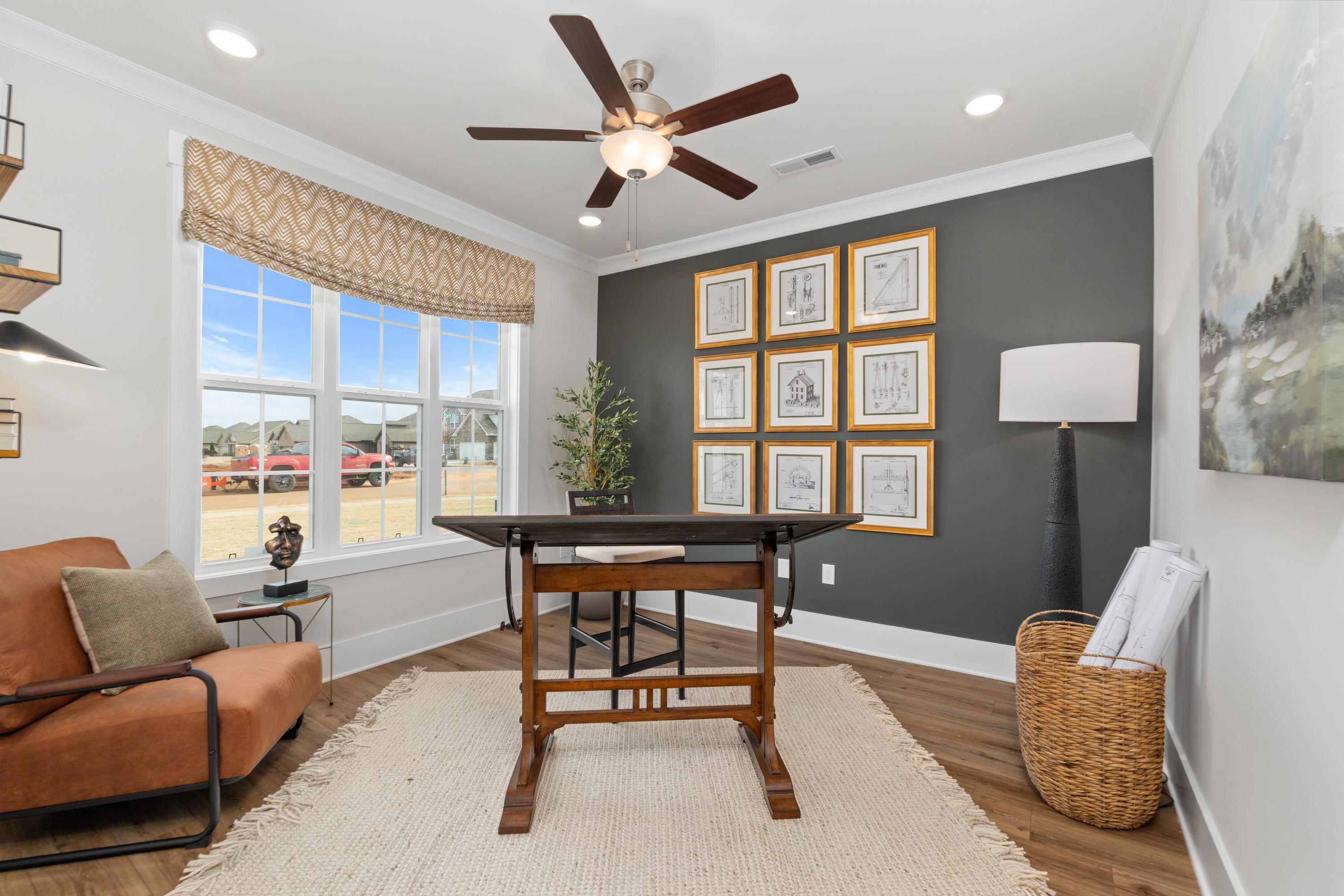 Cozy home office in Briercreek Meridianville AL with wooden drafting desk, orange armchair, framed art on gray wall, hardwood floors