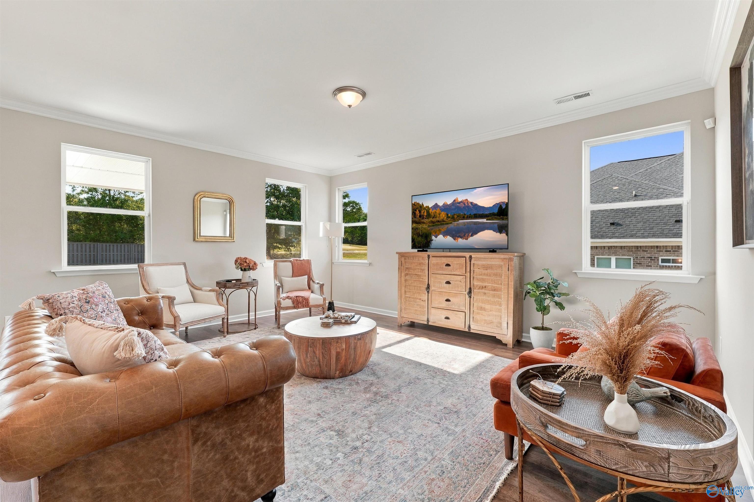 Bright living room with leather sofa, accent chairs, and natural light in Davidson Homes Arcadia E, Riverton Preserve, Huntsville