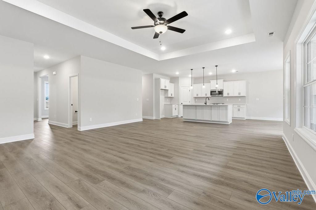 Open-concept kitchen with white island cabinets, pendant lights, dual ceiling fans, and hardwood floors in Davidson Homes The Rockford B, Hartselle, AL